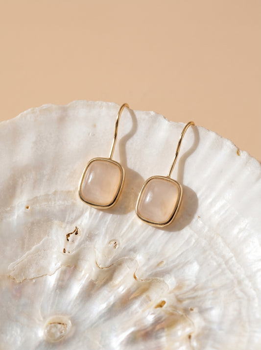 Close-up of rose quartz hook earrings with gold plated finish – natural gemstone detail