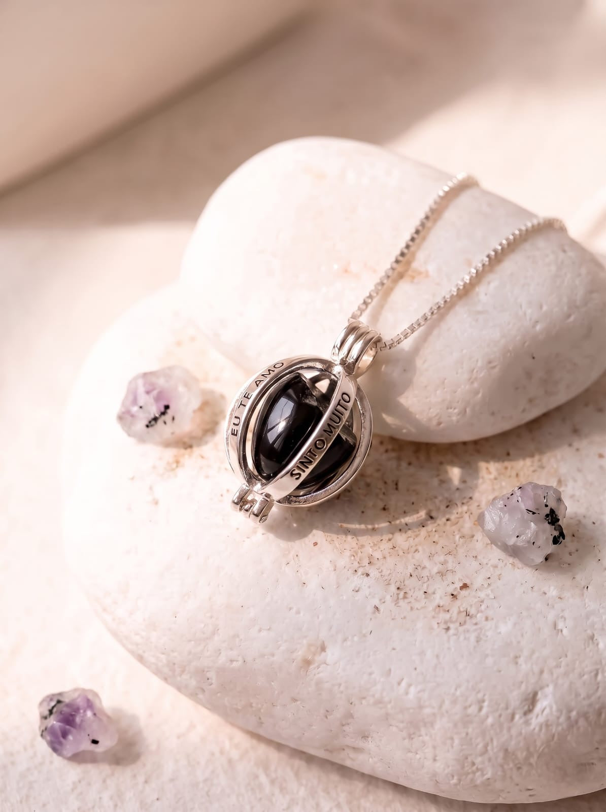 StoneCraft Jewellery Angel Caller Necklace Rhodium Plated with Black Agate displayed on white pebble stones with amethyst crystals
