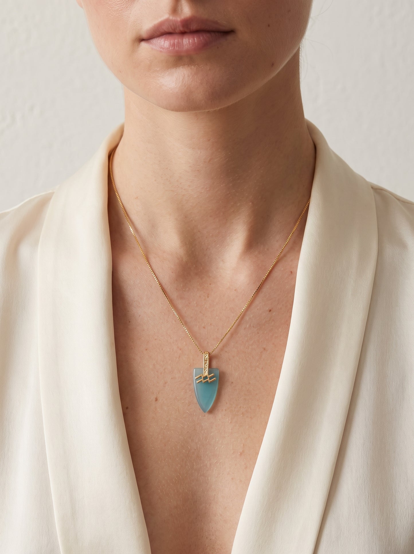 Aquarius agate pendant necklace with gold-plated box chain worn by a woman in a white blazer showing full neckline