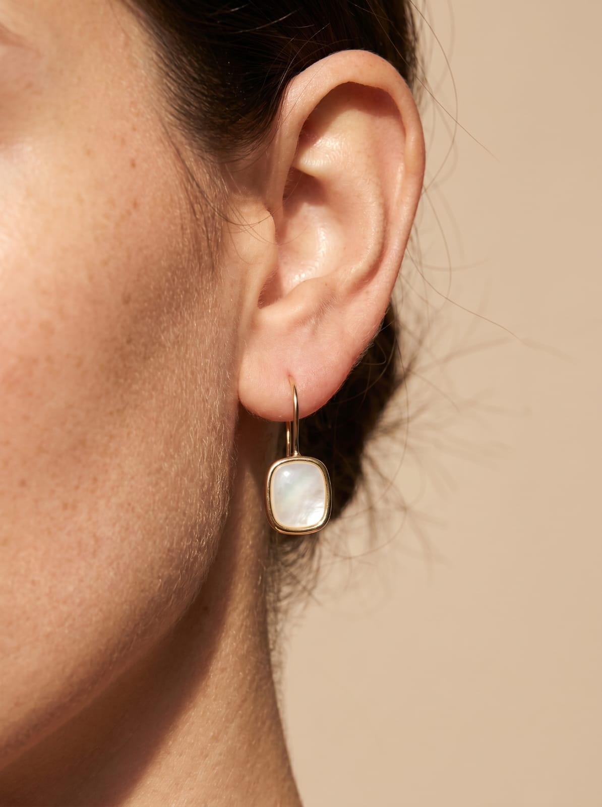 "Mother of pearl rectangle earring worn on ear, gold-plated hook, soft iridescent shimme