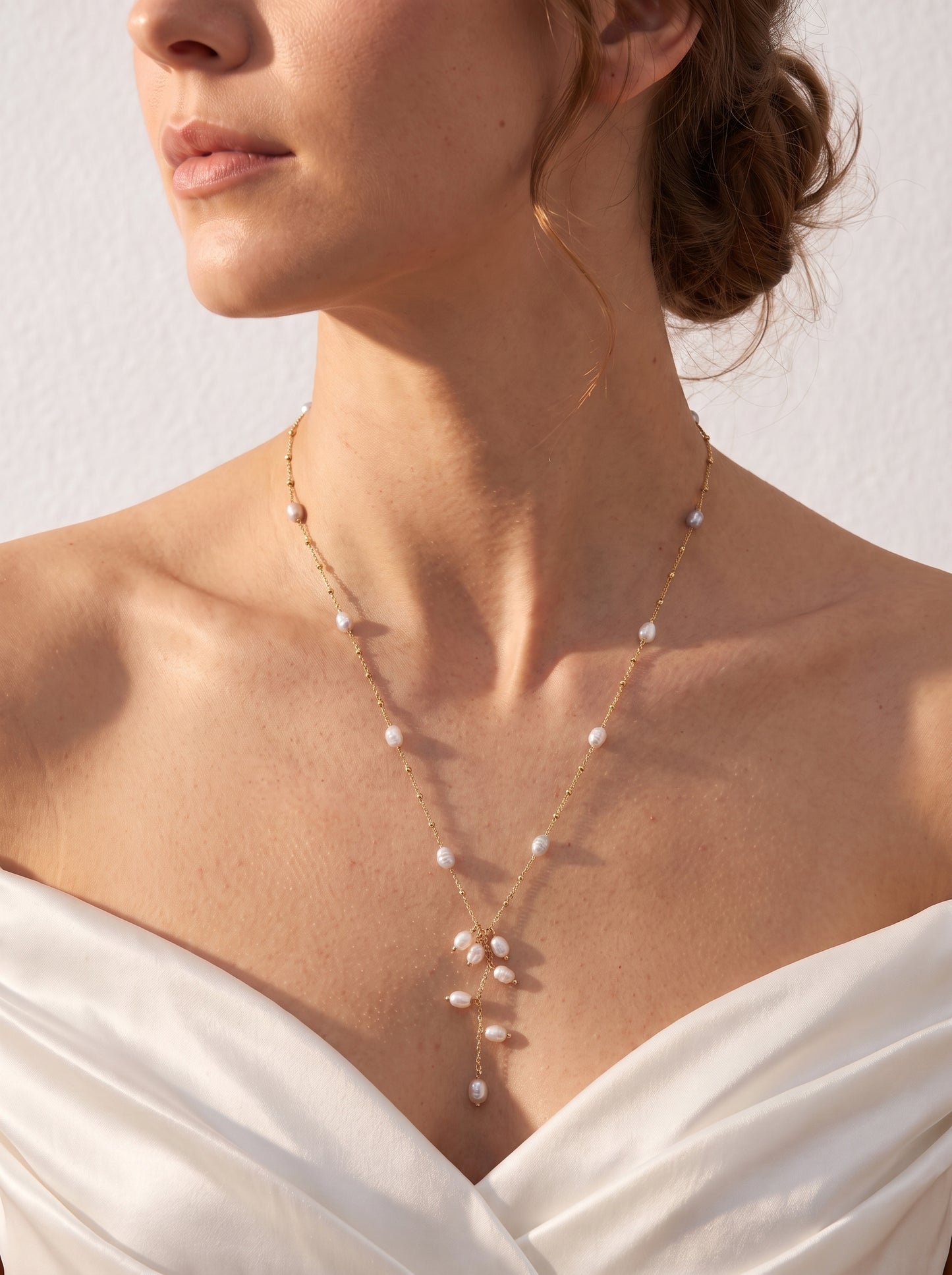 Long freshwater pearl lariat necklace worn over a white shirt showing the cascading pearl drop detail