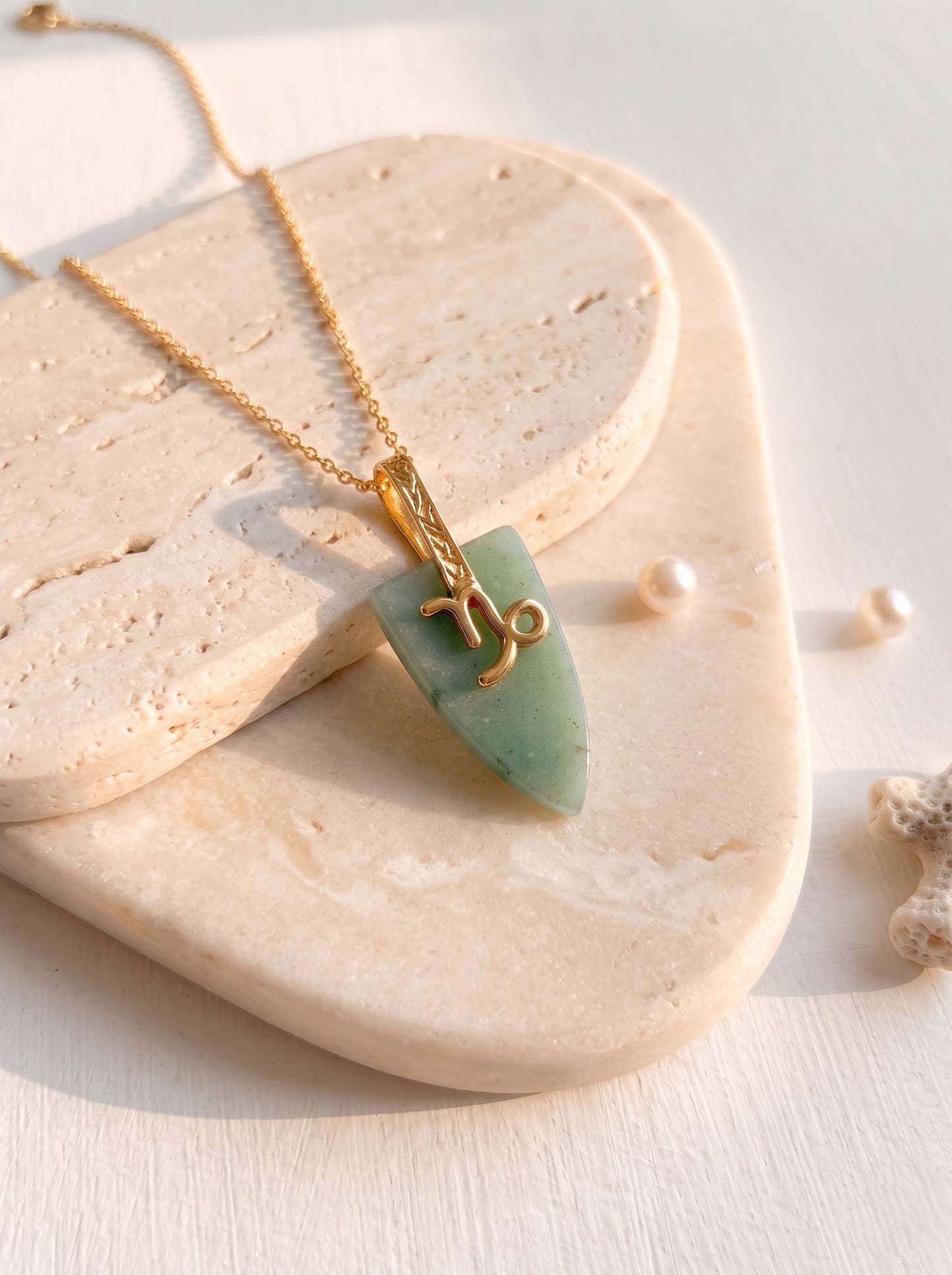 Woman wearing StoneCraft Jewellery green aventurine Capricorn zodiac arrowhead pendant necklace on gold chain, close-up decolletage view.