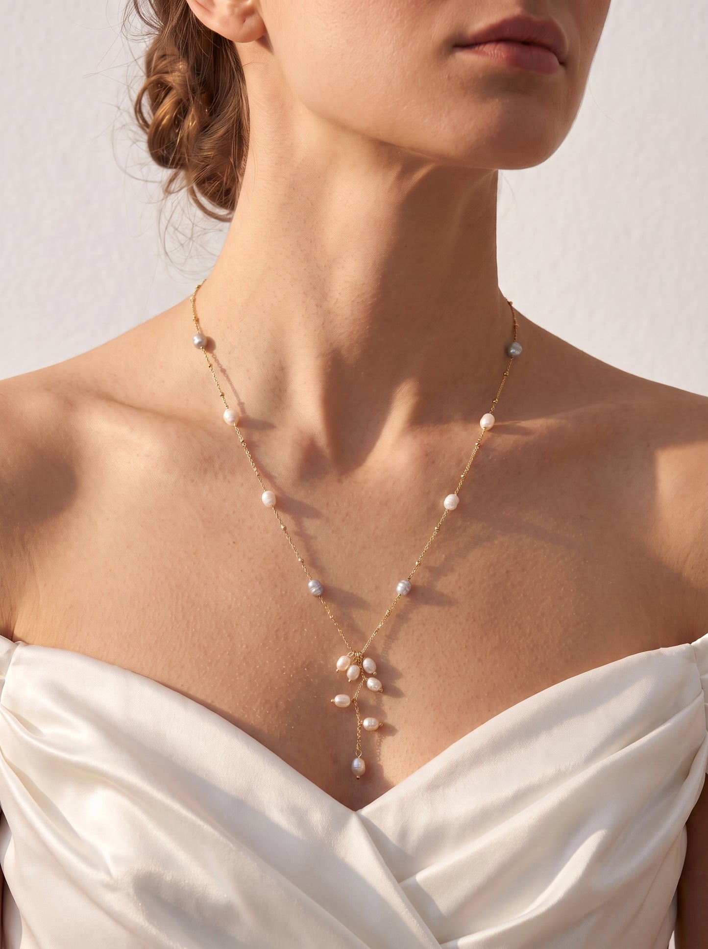 Long freshwater pearl lariat necklace worn over a white shirt showing the cascading pearl drop detail