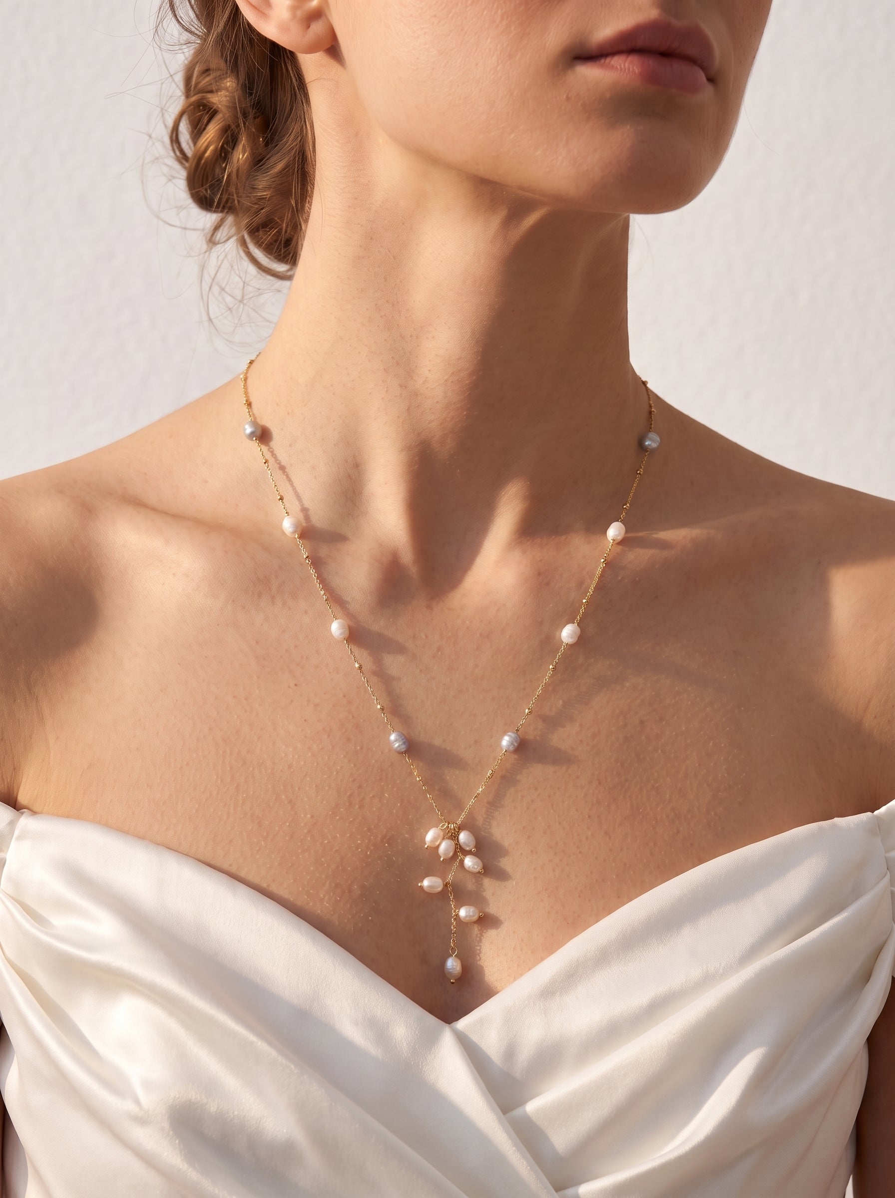 Long freshwater pearl lariat necklace worn over a white shirt showing the cascading pearl drop detail