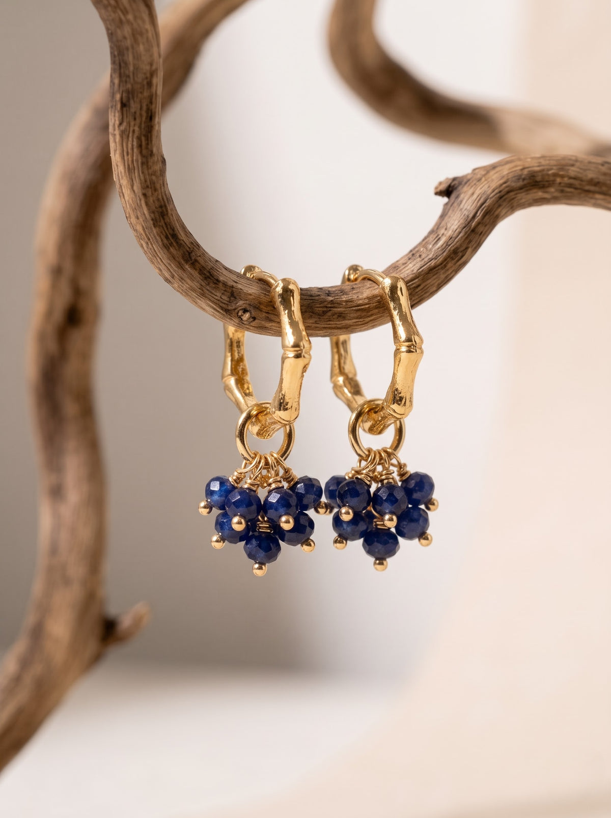 Gold-plated hoop earring with lapis lazuli bead cluster hanging against a plain light background, StoneCraft Jewellery