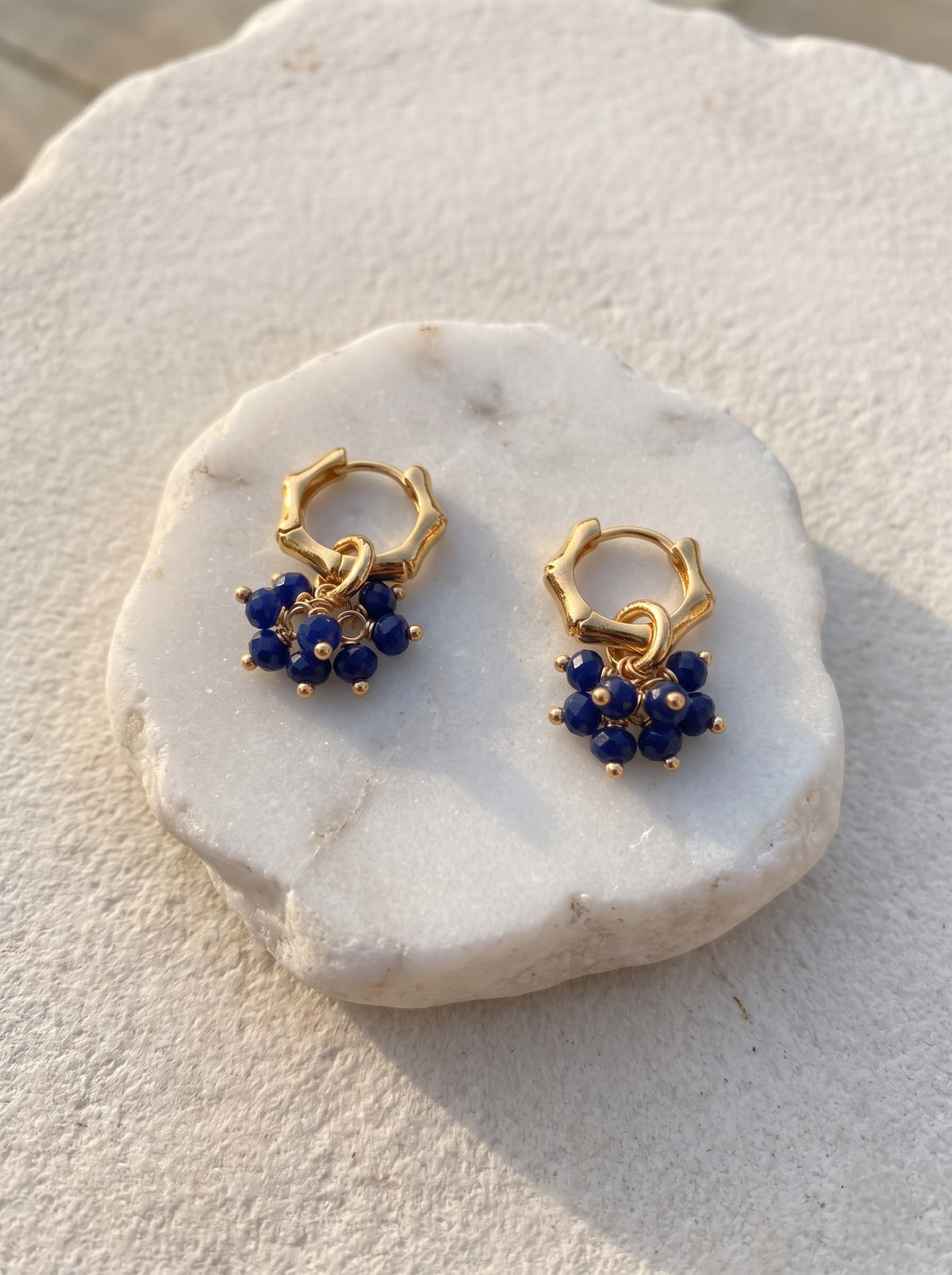 Model wearing gold-plated hoop earring with lapis lazuli bead cluster, StoneCraft Jewellery