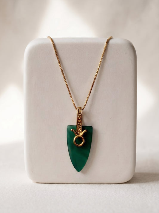 Gold-plated box chain necklace with green agate arrowhead pendant and Taurus zodiac bail displayed on a white jewellery stand