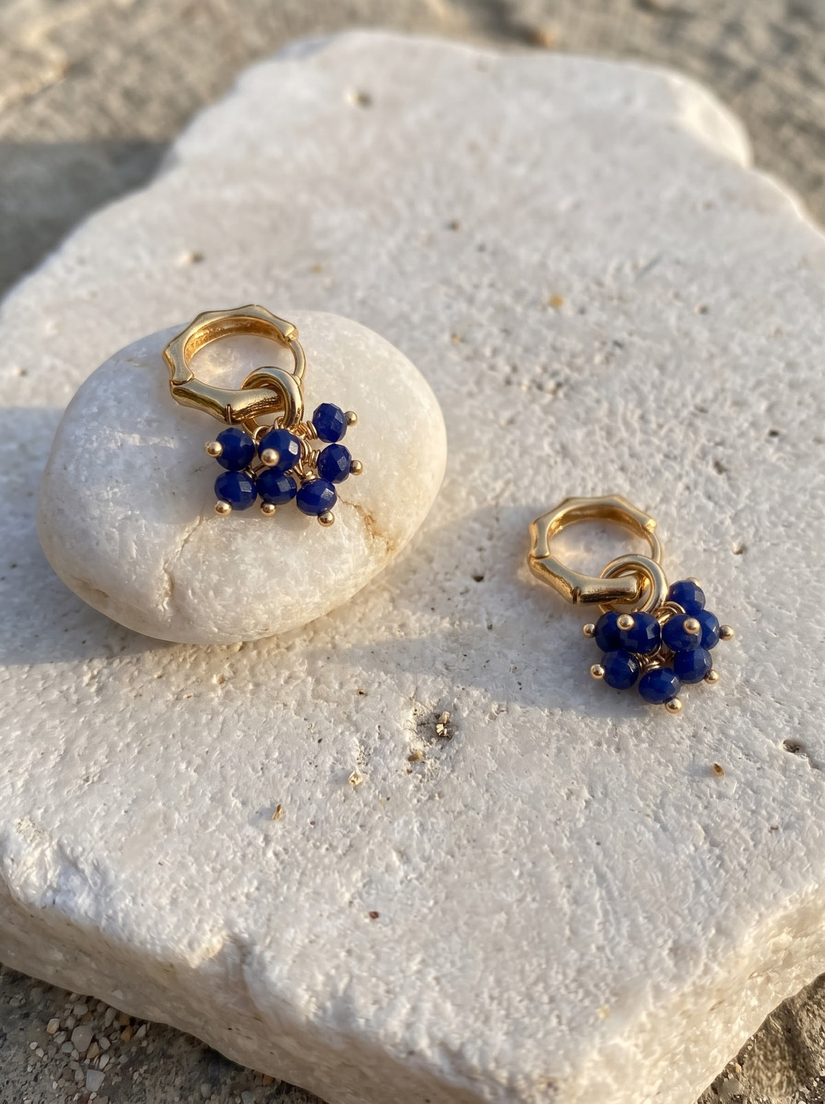 Gold-plated hoop earrings with lapis lazuli bead clusters displayed flat on a light background, StoneCraft Jewellery