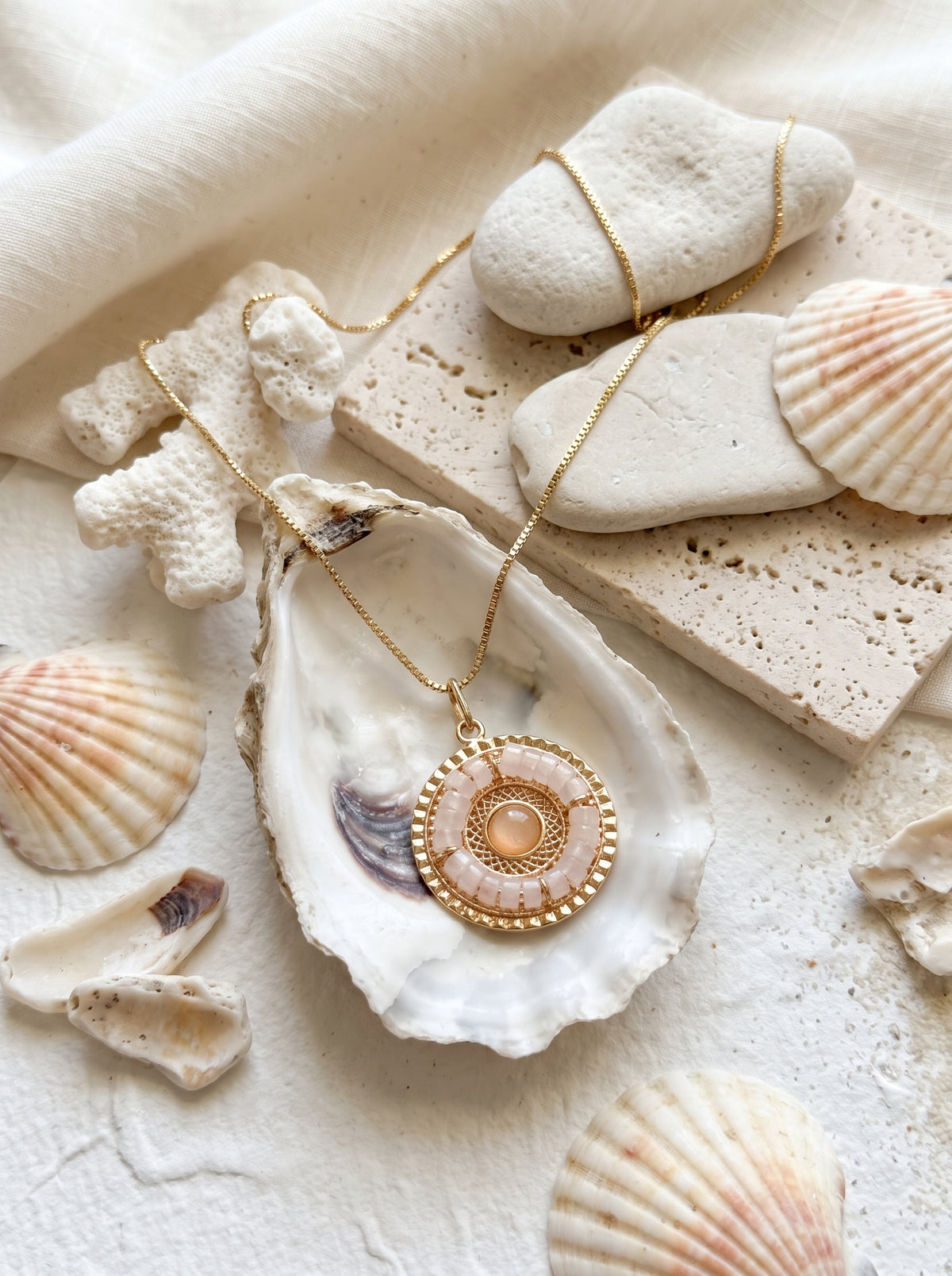 mandala rose quartz pendant in oyster shell surrounded by seashells — StoneCraft Jewellery