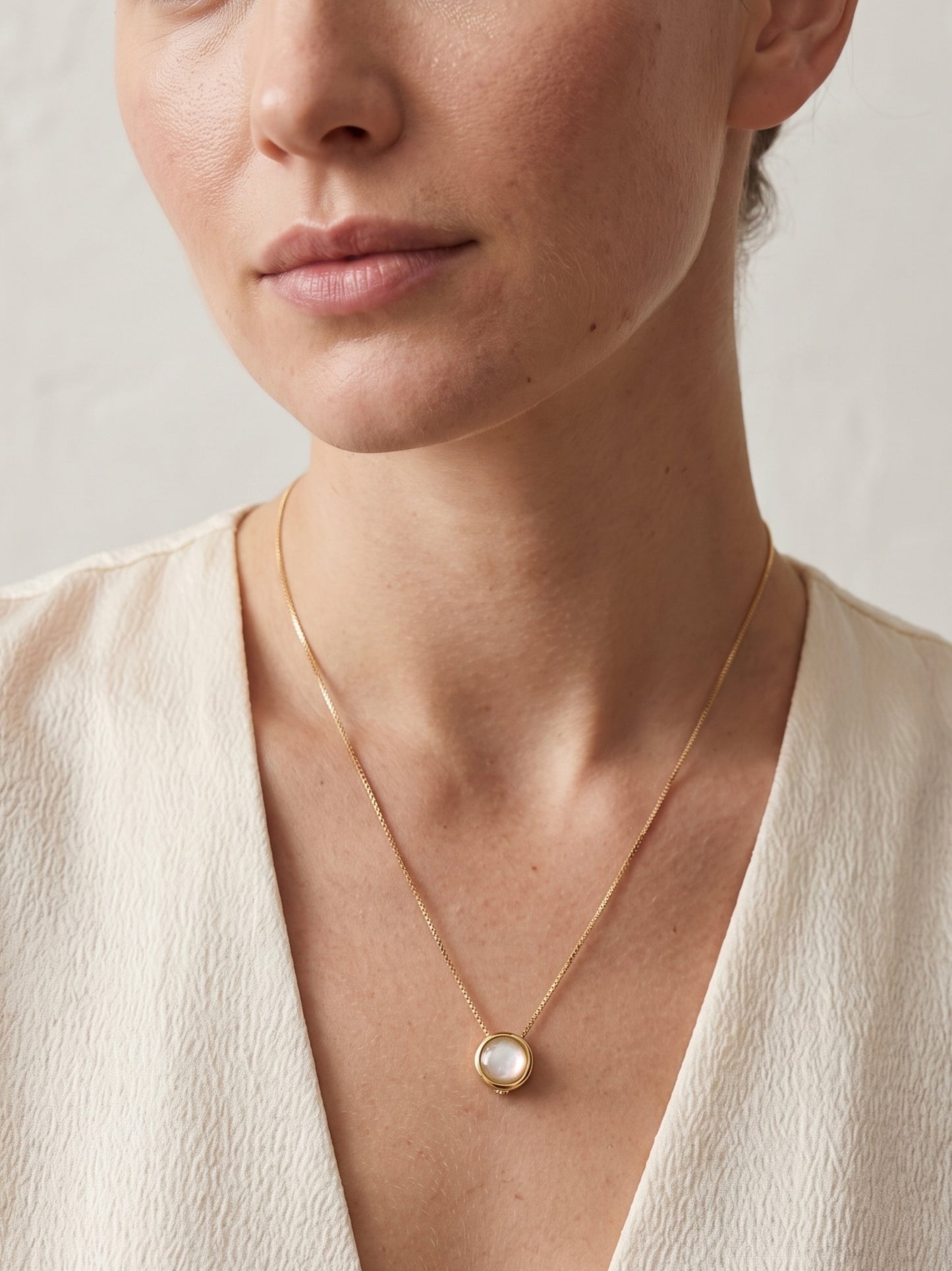 Opalite Lariat Slide Necklace gold-plated worn on model in cream V-neck top, round opalite pendant at neckline — StoneCraft Jewellery