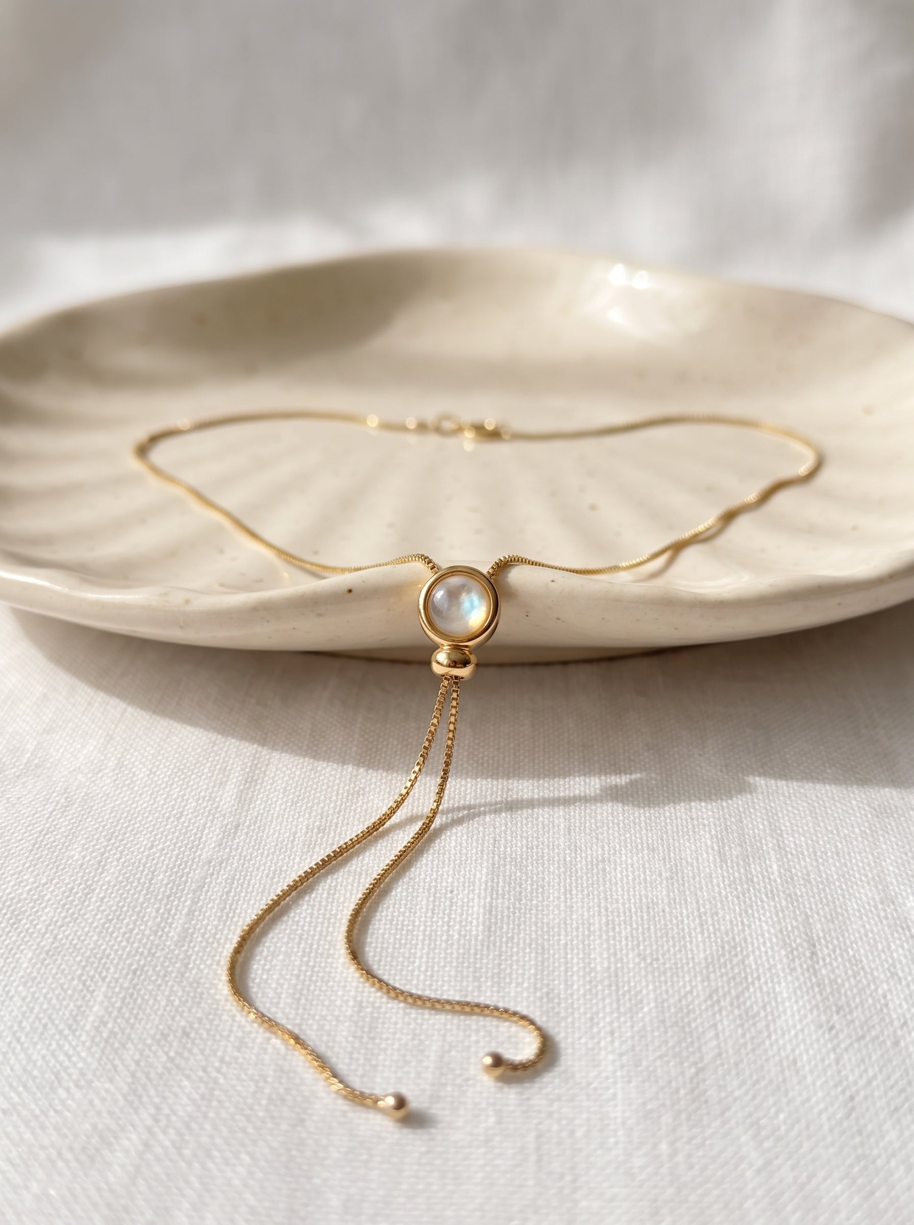 Opalite Lariat Slide Necklace gold-plated flat lay on white ceramic dish showing opalite pendant and chain detail — StoneCraft Jewellery