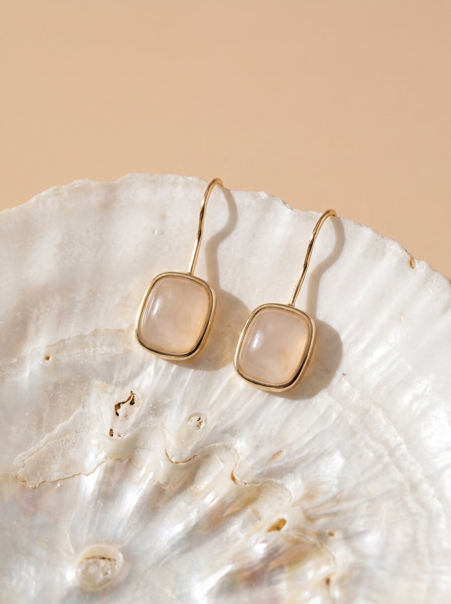 Close-up of rose quartz hook earrings with gold plated finish – natural gemstone detail