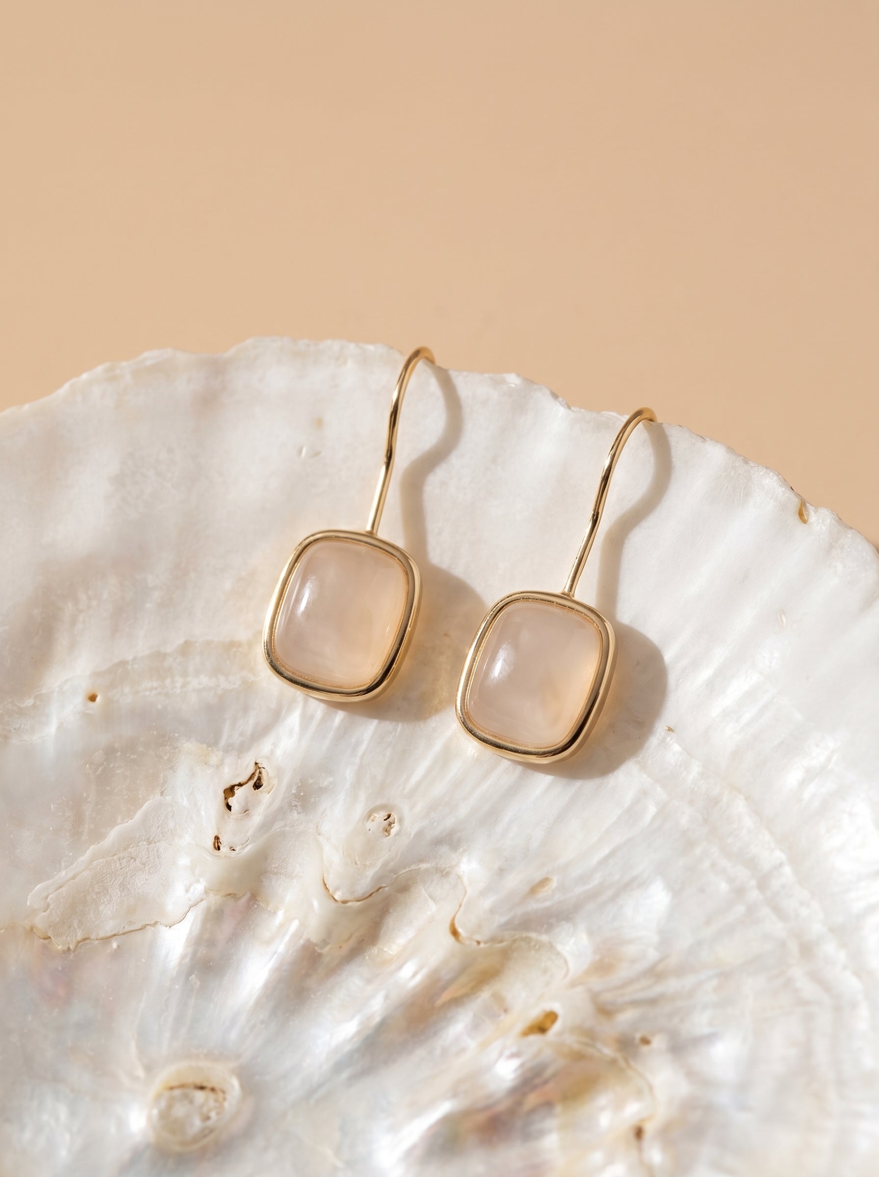 Close-up of rose quartz hook earrings with gold plated finish – natural gemstone detail