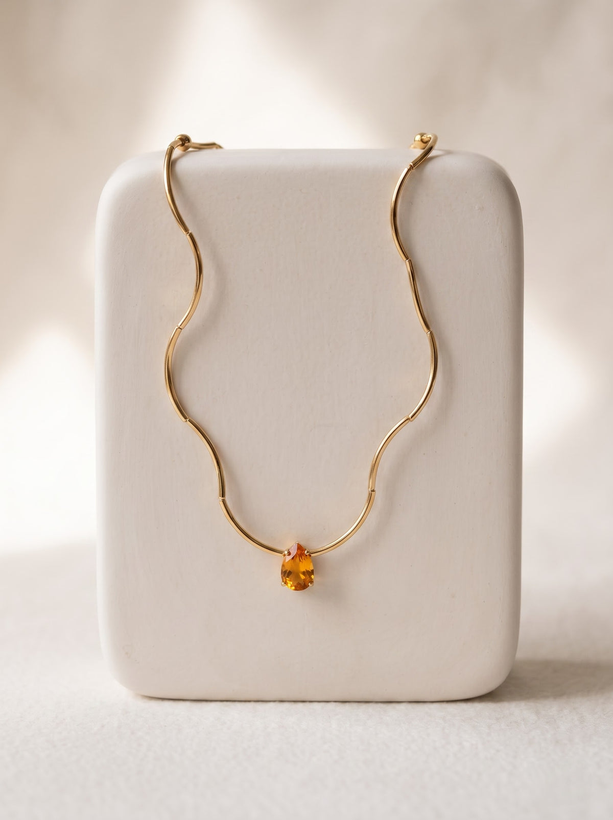 StoneCraft Jewellery Gold Wave Snake Chain Necklace with orange Crystal Pendant displayed on white jewellery stand