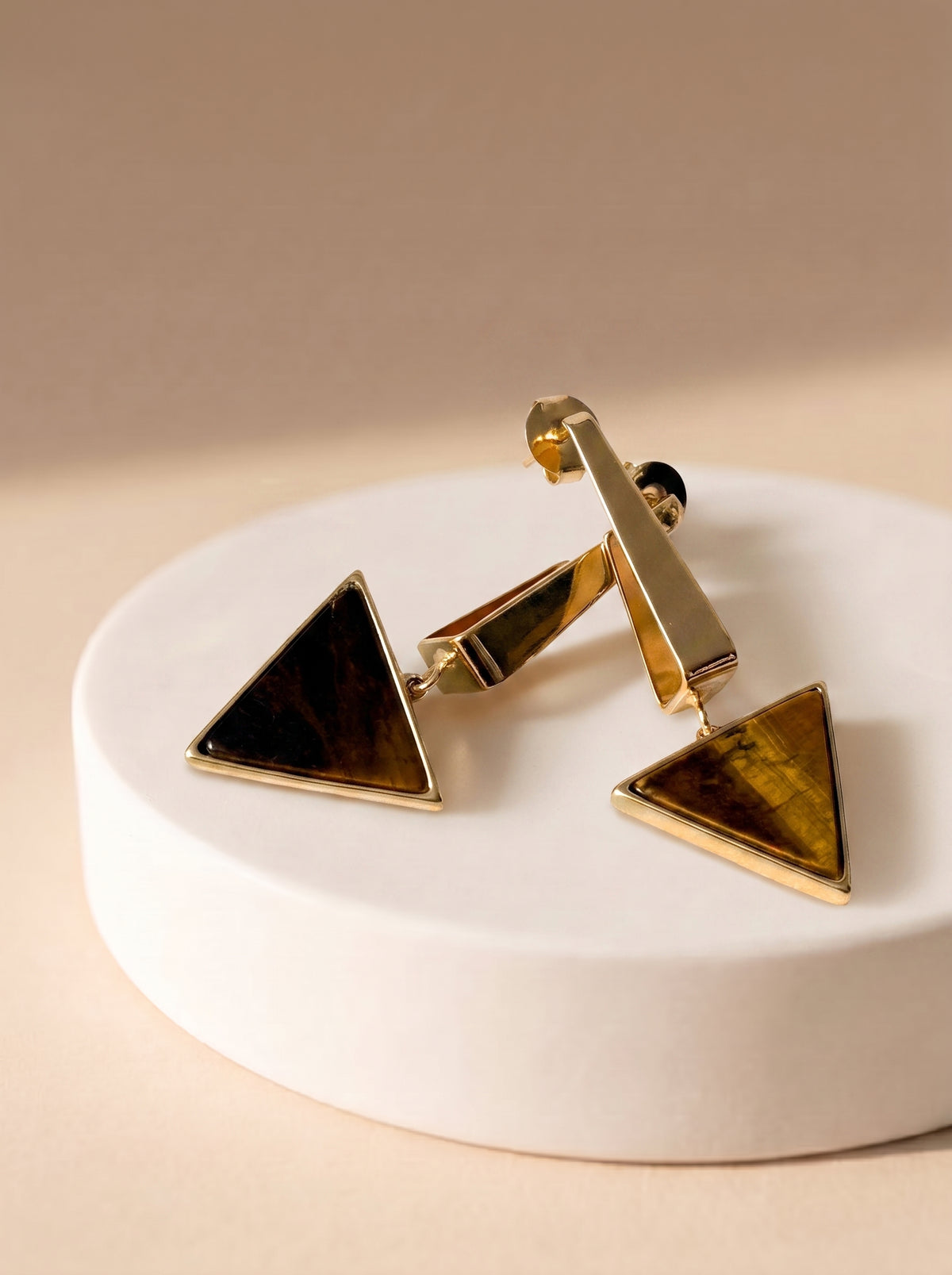 StoneCraft Jewellery gold-plated Tiger’s Eye triangle drop earrings displayed in a dark dish.