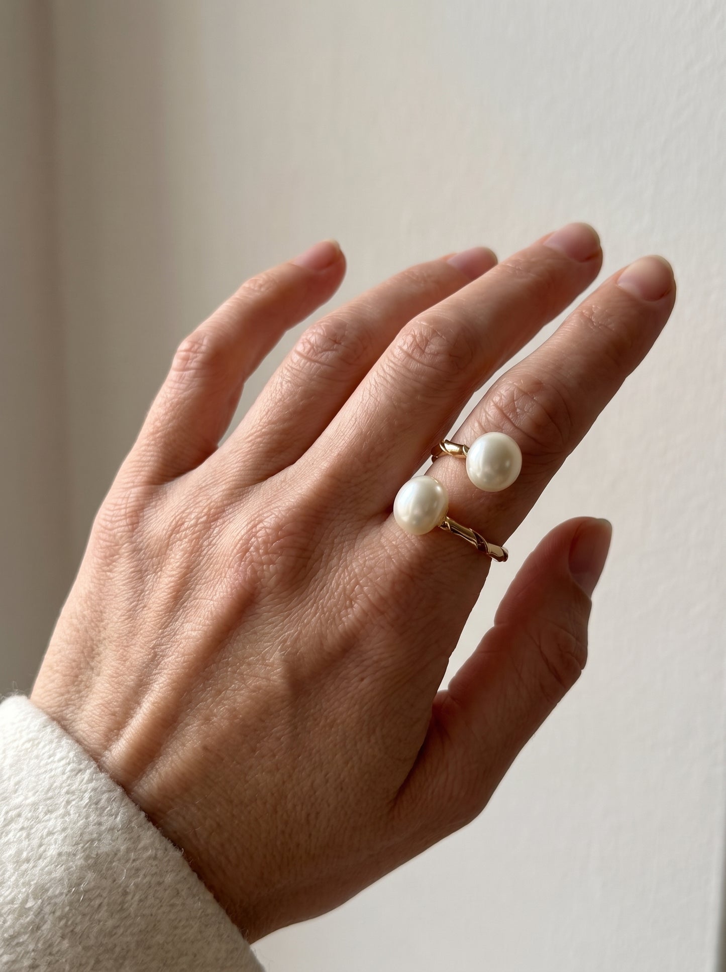 Close-up of dual pearl twisted gold ring on hand