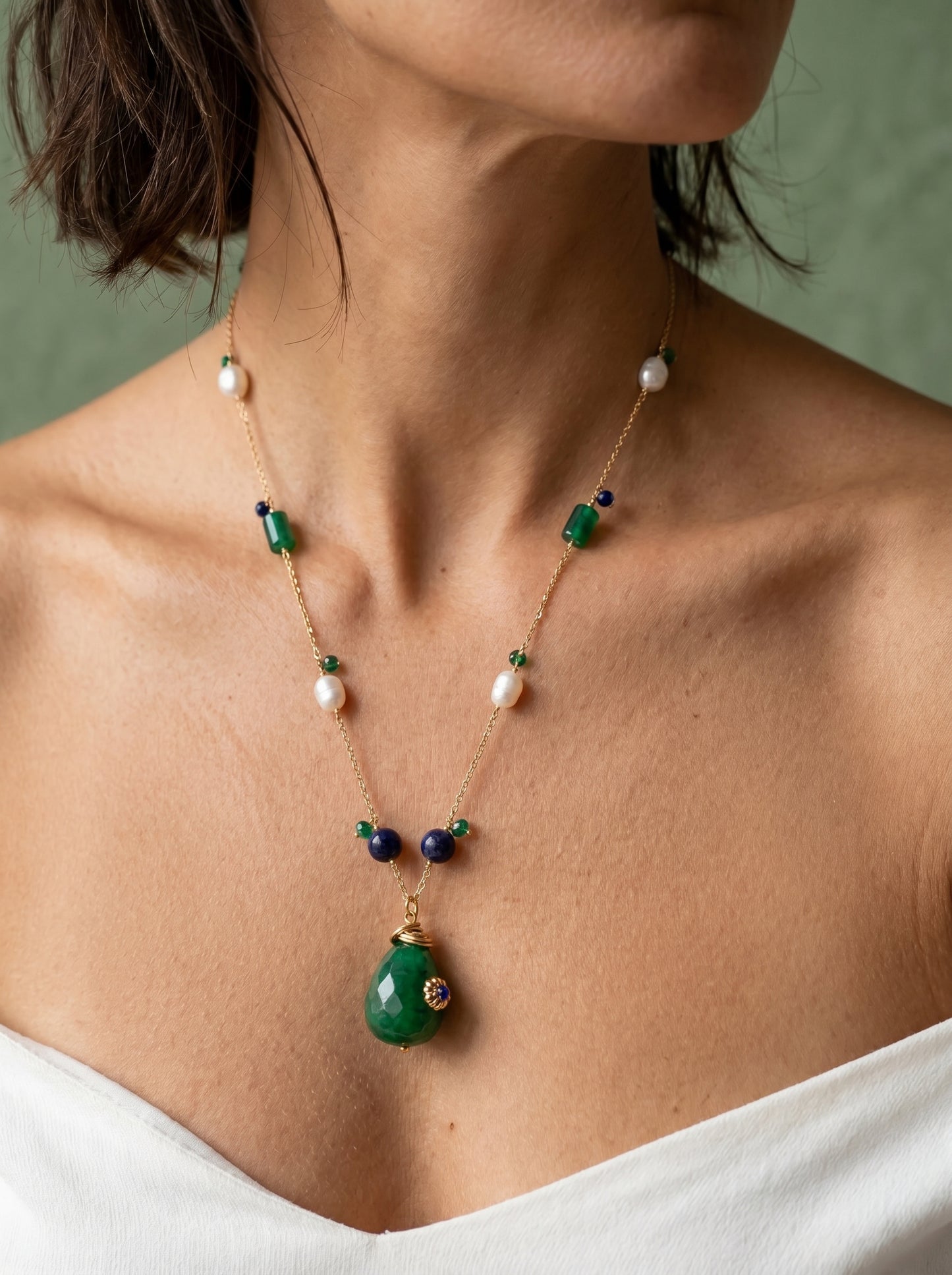 Close-up of green jade teardrop pendant with gold floral cap, pearl and jade beads on gold chain