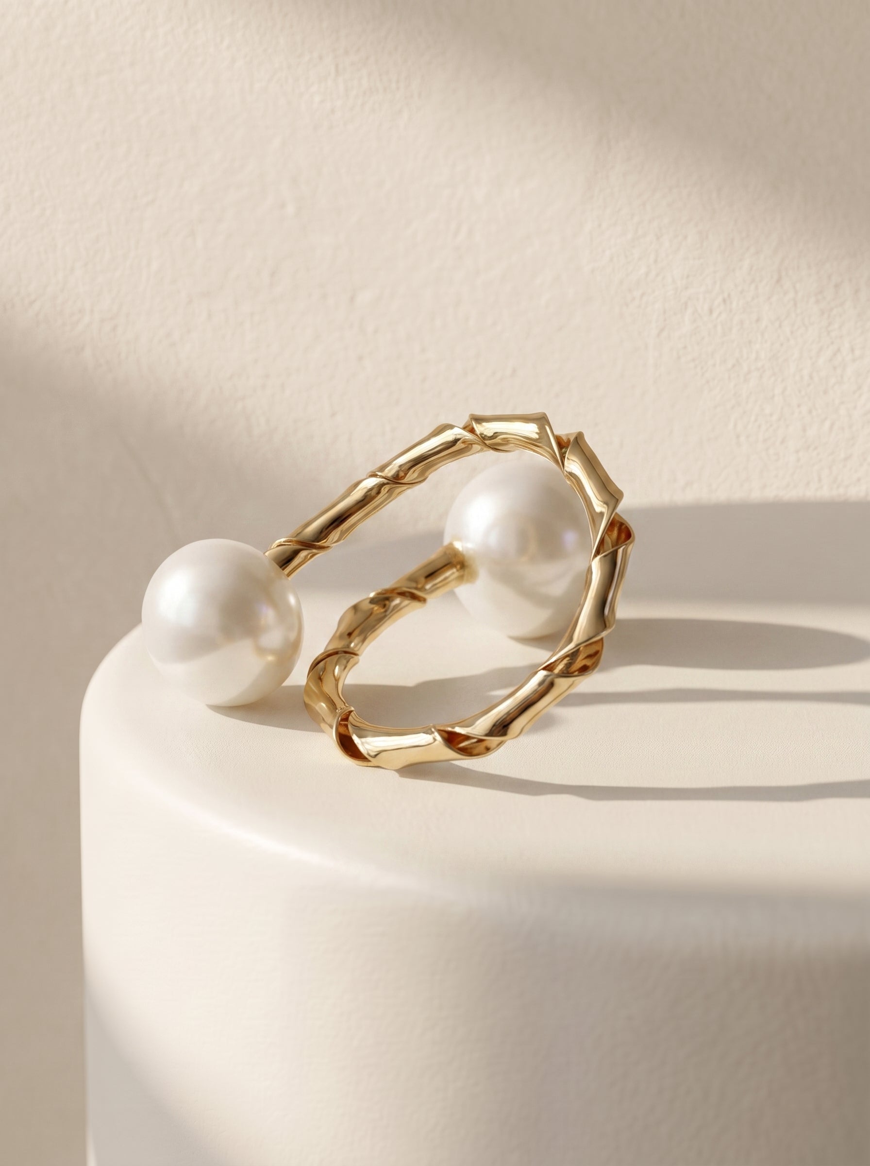 Dual pearl twisted gold ring flat lay on white surface