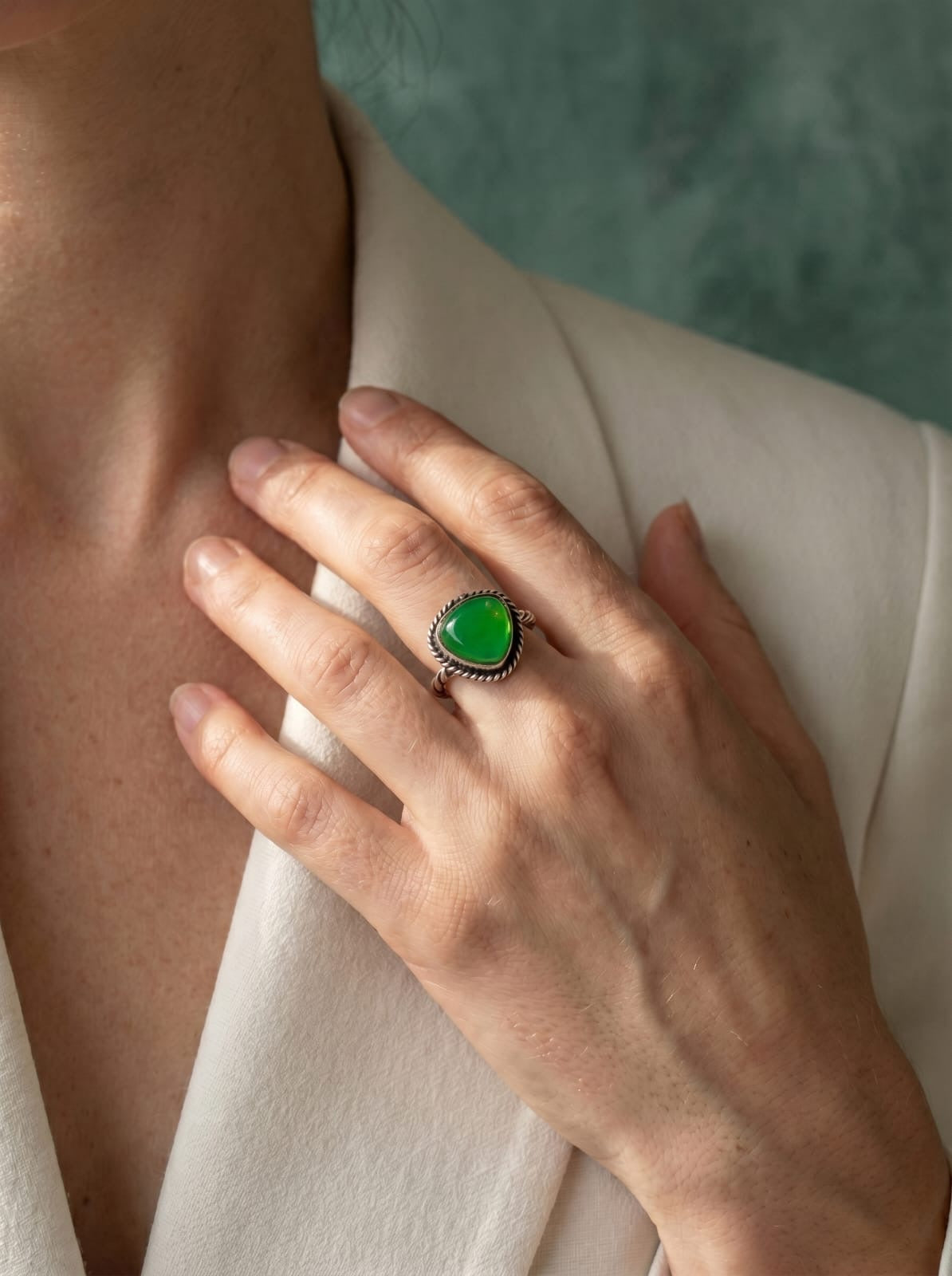 Hand wearing a green jade ring with a textured background
