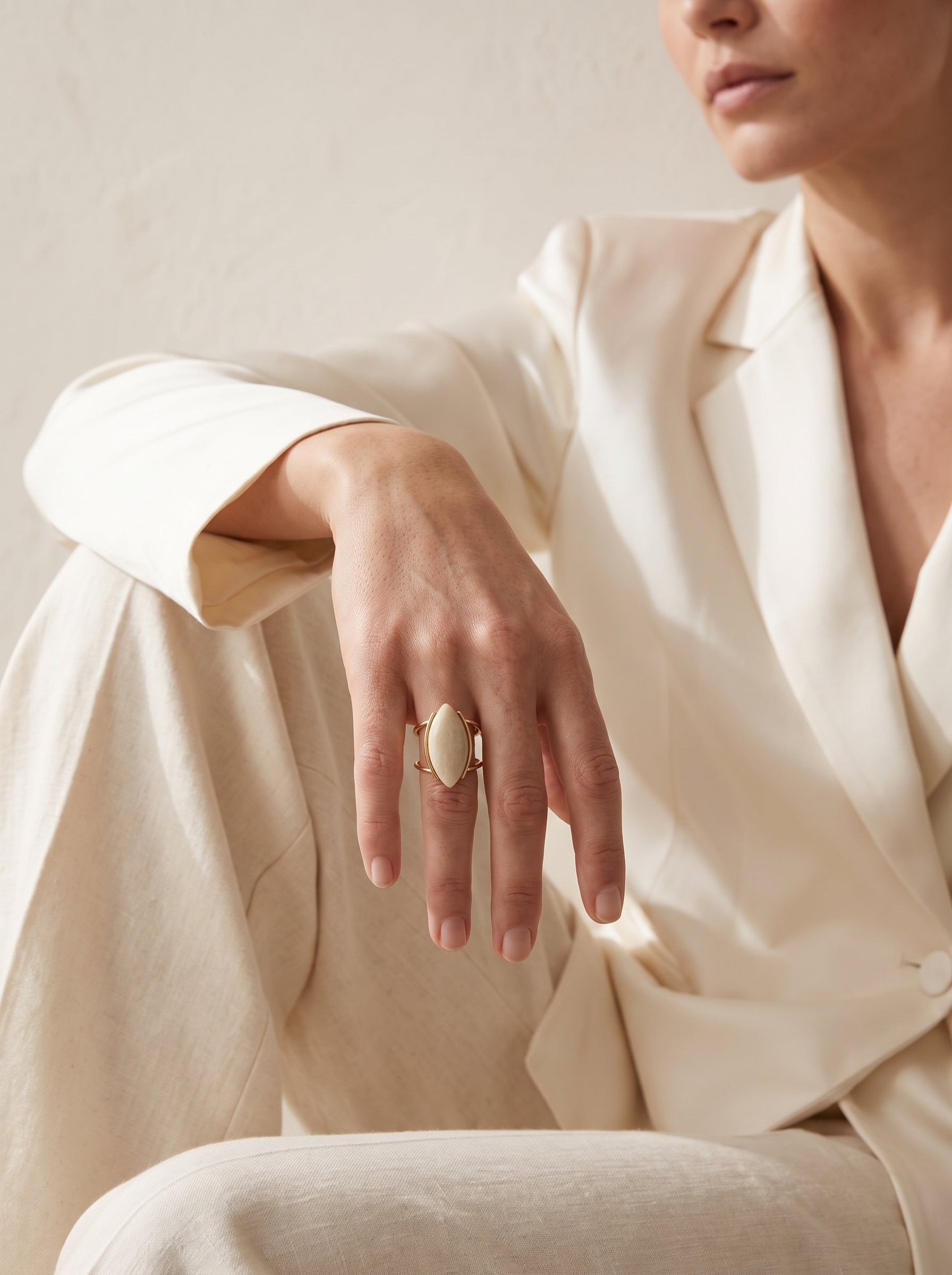 Model wearing beige amazonite marquise gold ring, hand resting on shoulder, styled with white blazer – StoneCraft Jewellery
