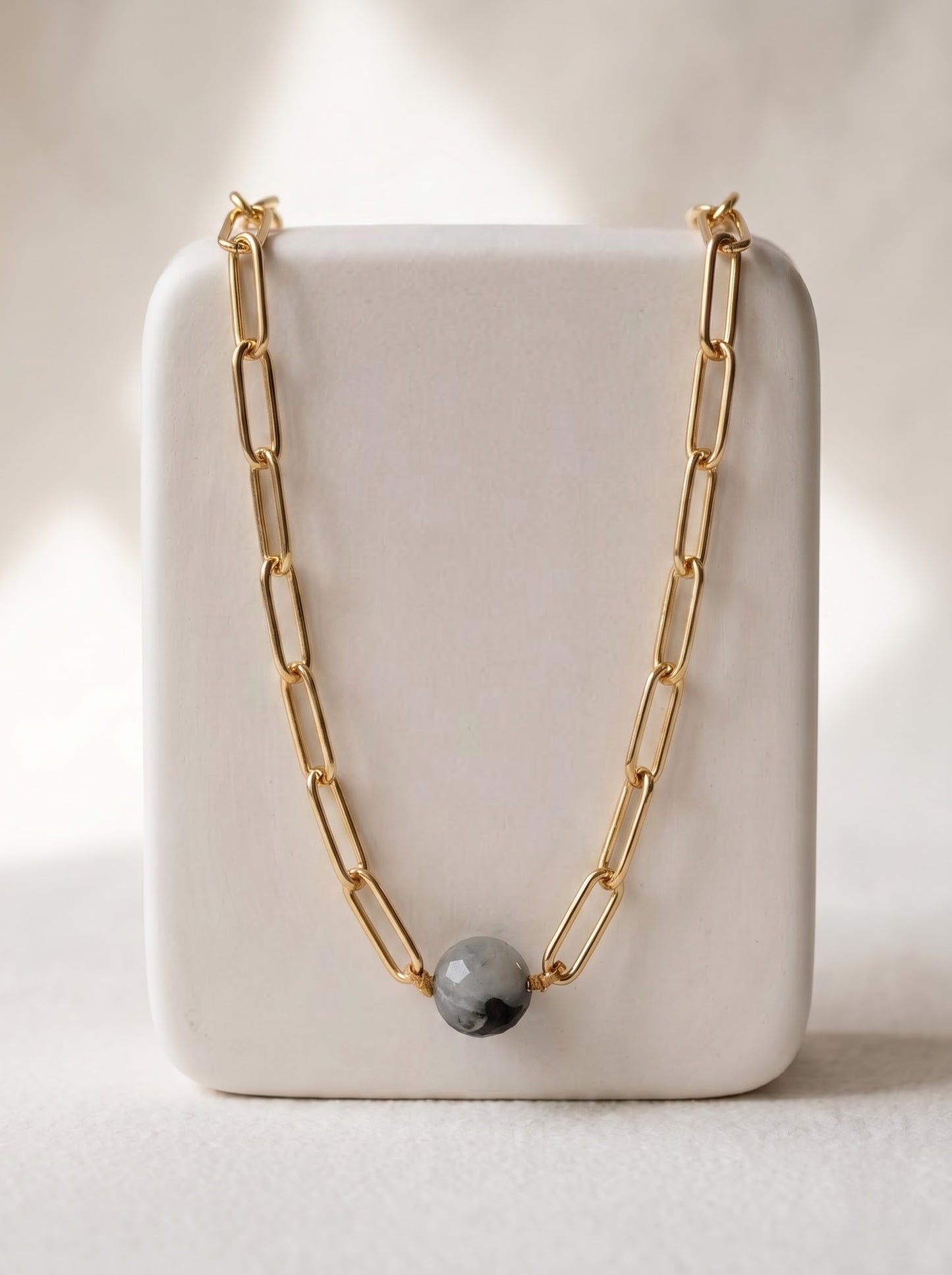 StoneCraft Jewellery black rutile quartz sphere gold paperclip chain necklace, displayed on white ceramic jewellery stand.