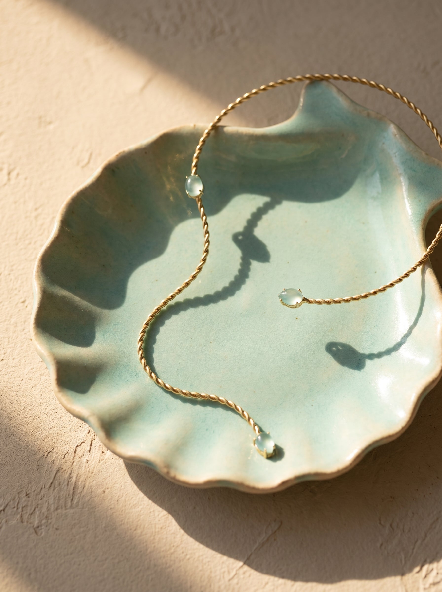 Close-up of faceted aqua green stones on twisted gold-plated rigid collar necklace — StoneCraft Jewellery