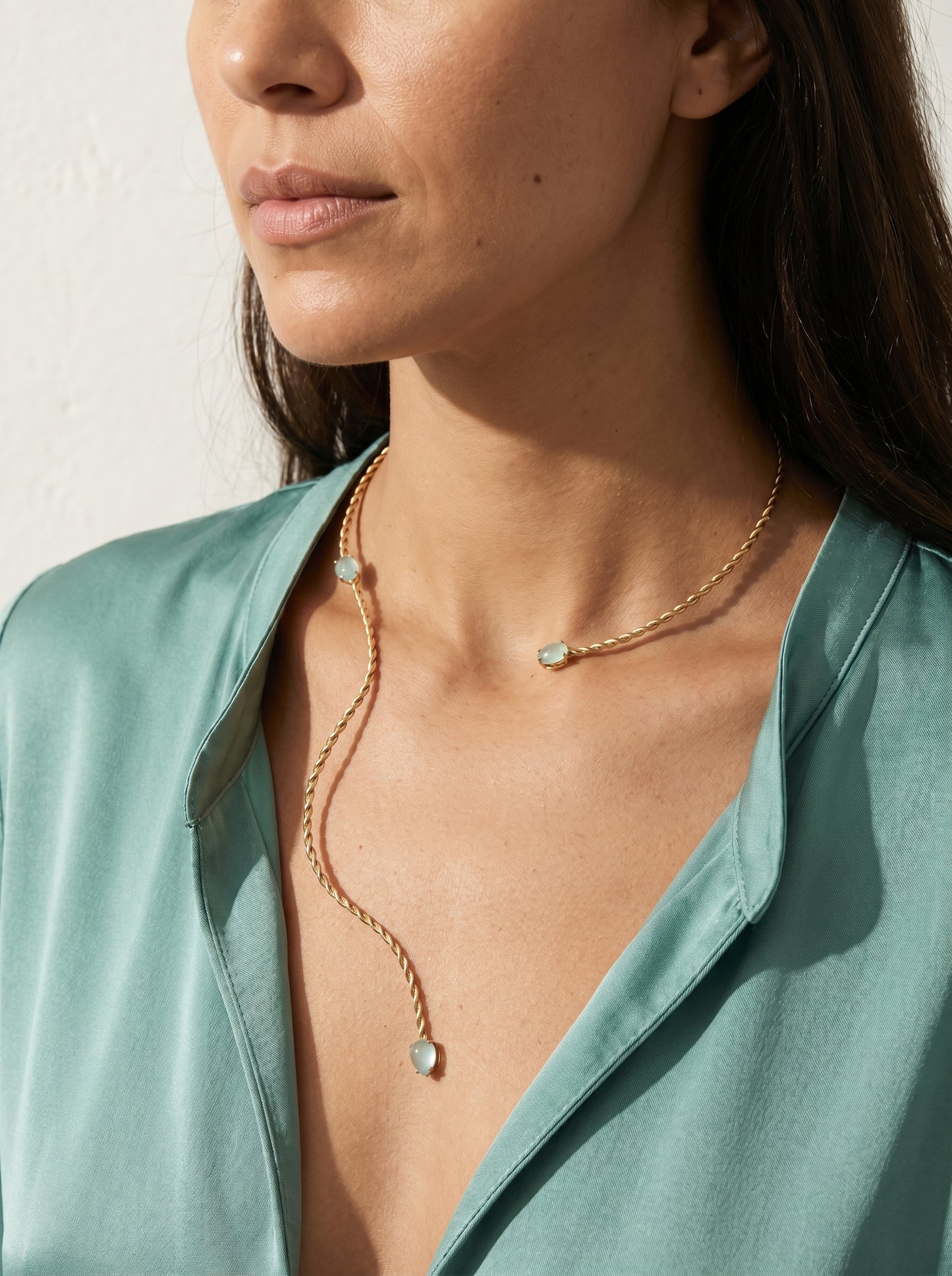 Twisted gold-plated collar necklace worn at neckline, sculptural asymmetric silhouette