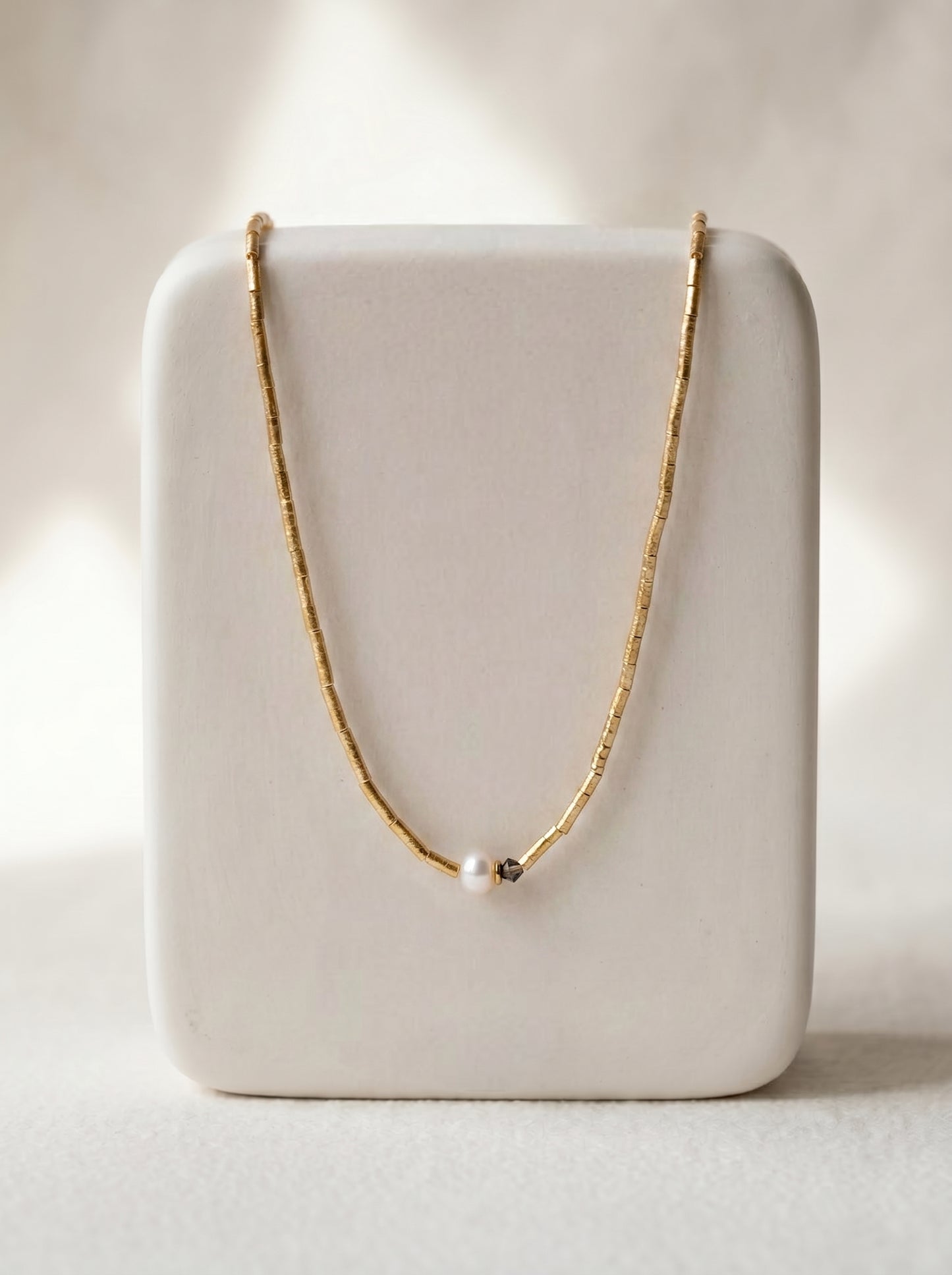 Crystal and pearl lariat necklace worn at neckline, gold-plated delicate chain with crystal accents