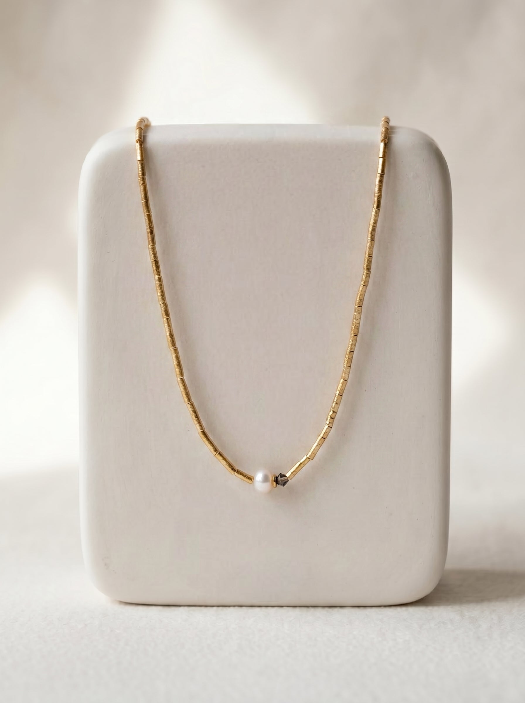 Crystal and pearl lariat necklace worn at neckline, gold-plated delicate chain with crystal accents