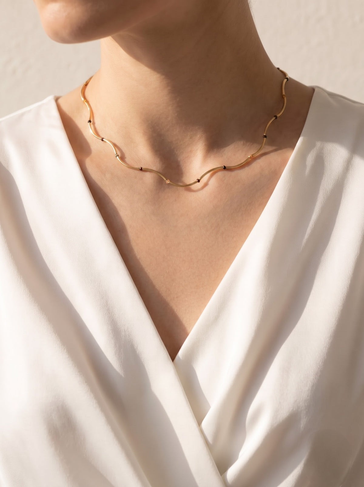 Woman wearing StoneCraft Jewellery Gold Wave Chain Necklace with Tiger's Eye Beads full neckline view on white wrap top