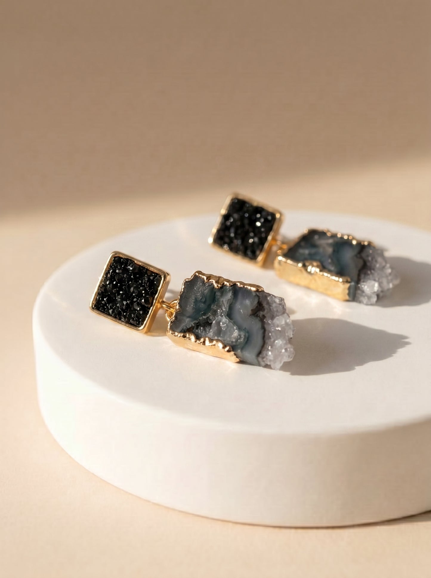 Black tourmaline and amethyst drop earrings flat lay on marble surface