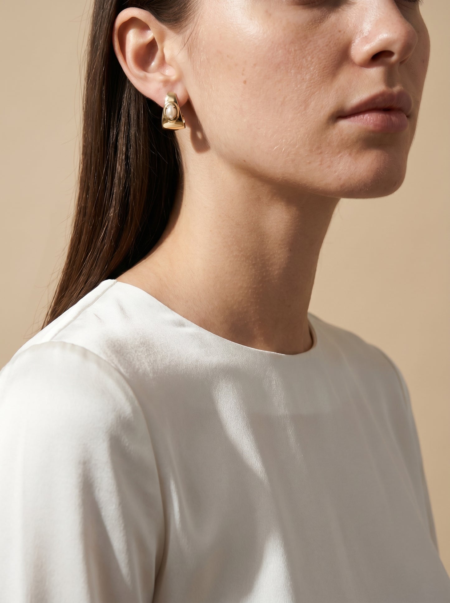 Model wearing gold-plated half hoop earrings with shell cabochon, side profile view