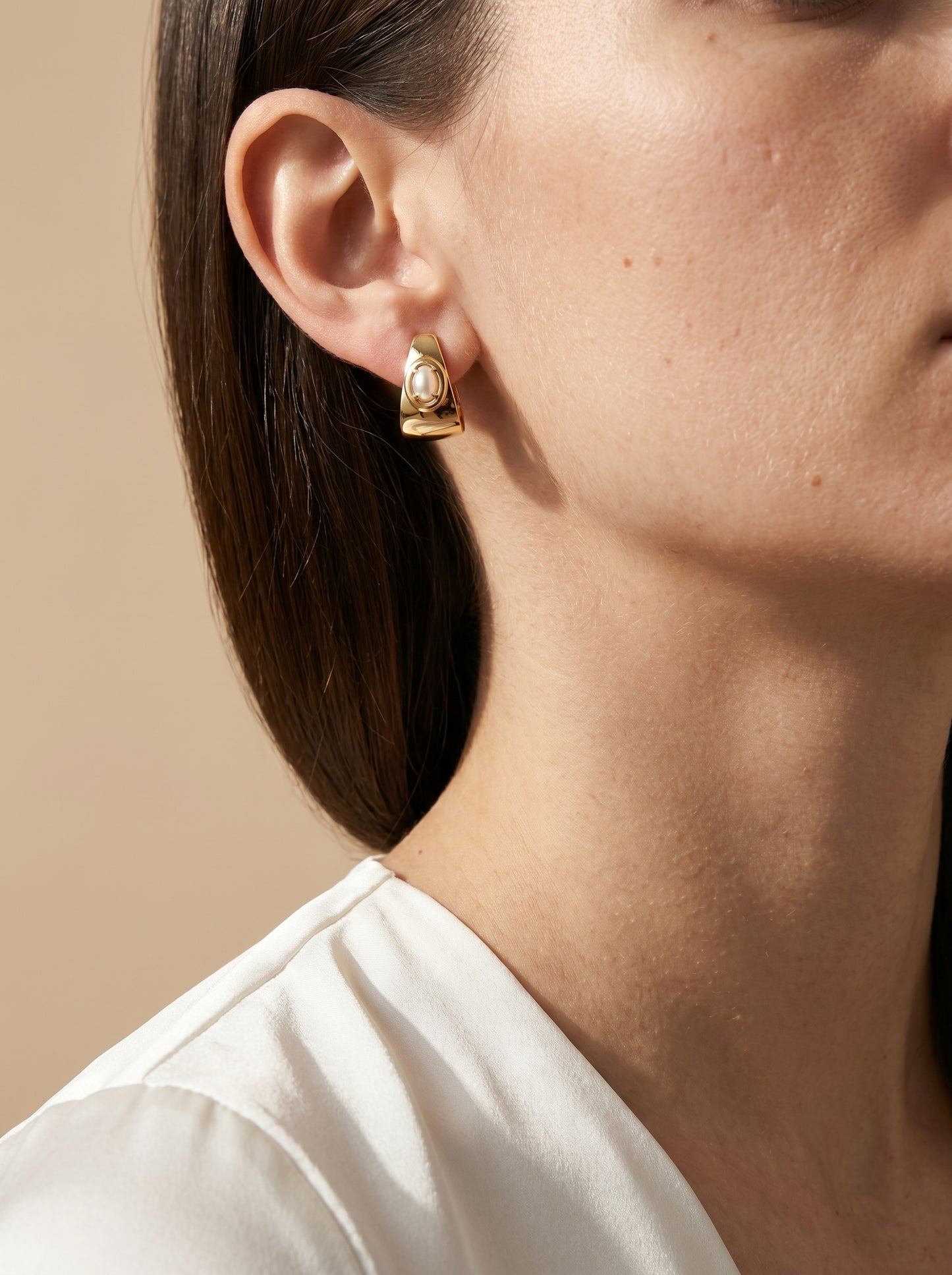 Model wearing gold-plated half hoop earrings with shell cabochon, side profile view
