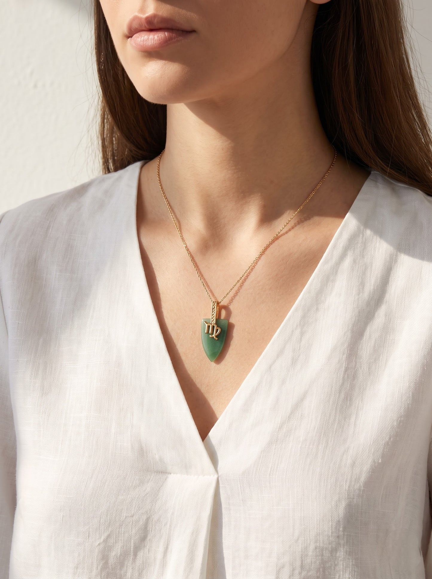 StoneCraft Jewellery green aventurine Virgo zodiac arrowhead pendant necklace on gold chain, styled flatlay with seashell and quartz crystal.