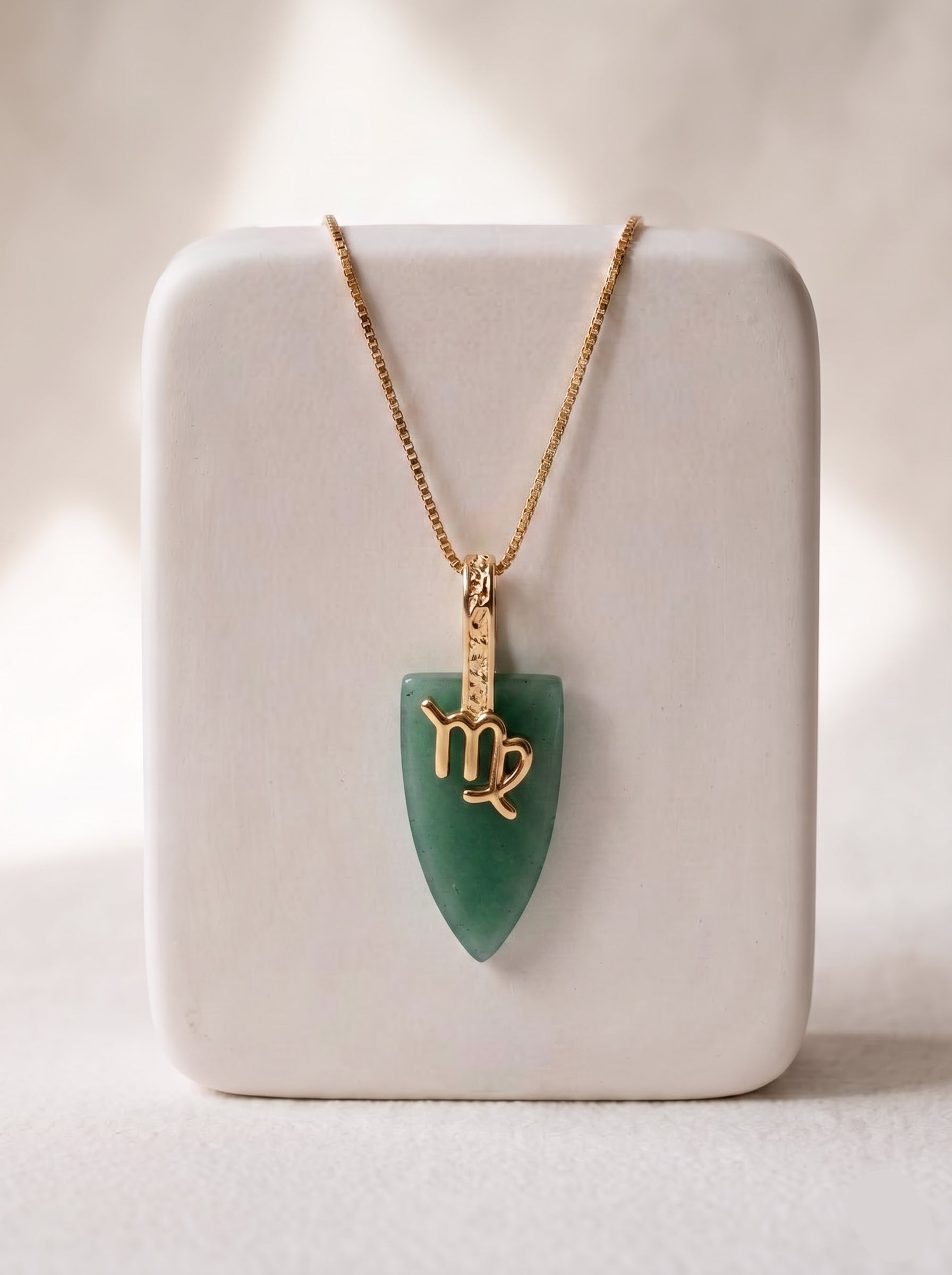 Woman wearing StoneCraft Jewellery green aventurine Virgo zodiac arrowhead pendant necklace on gold chain, minimal neutral background.