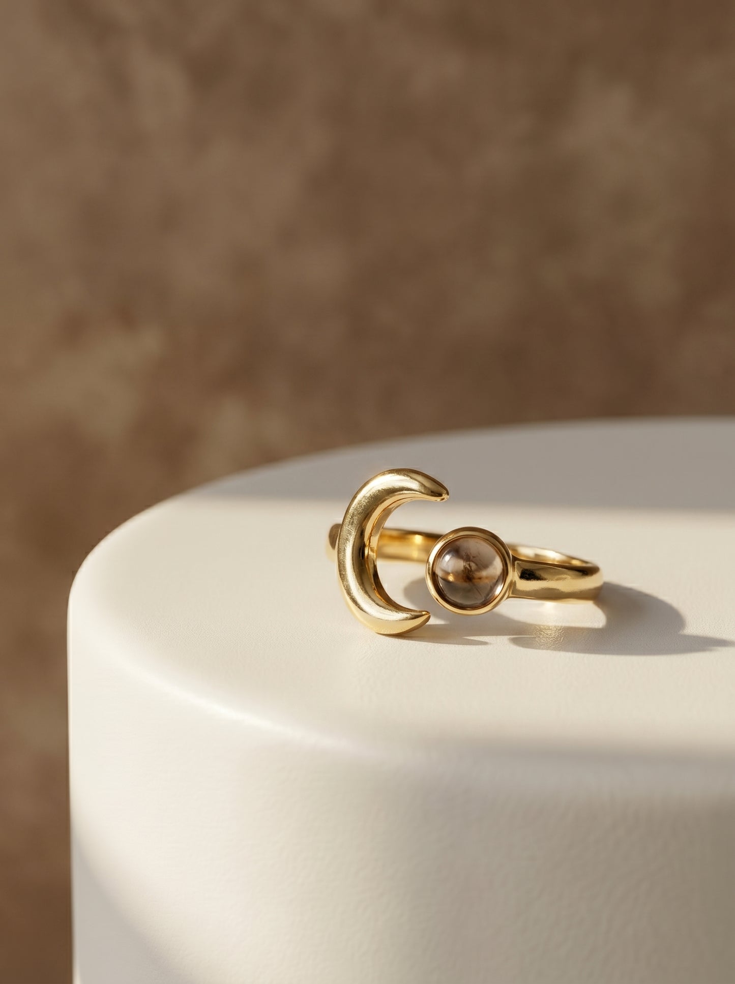 Gold ring with a central smoky quartz gemstone and a moon. 