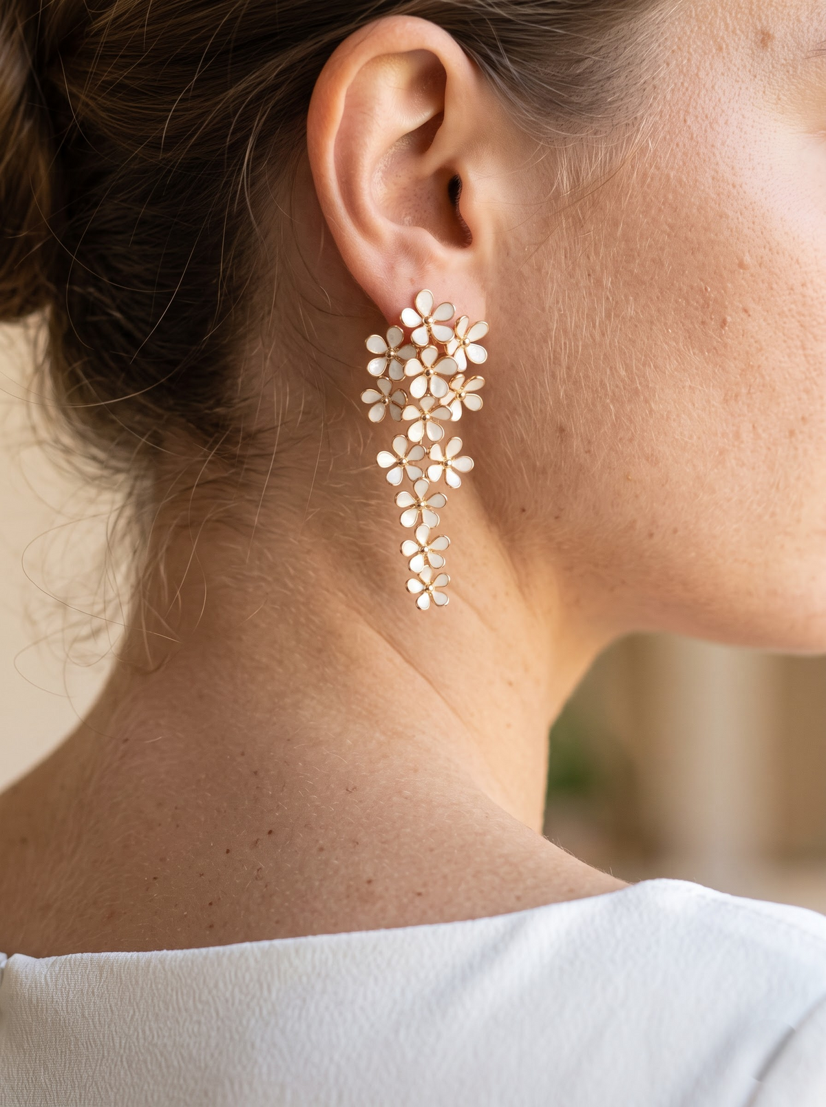 StoneCraft Jewellery white floral cascade earrings with gold-plated outlines displayed on a white round stand.
