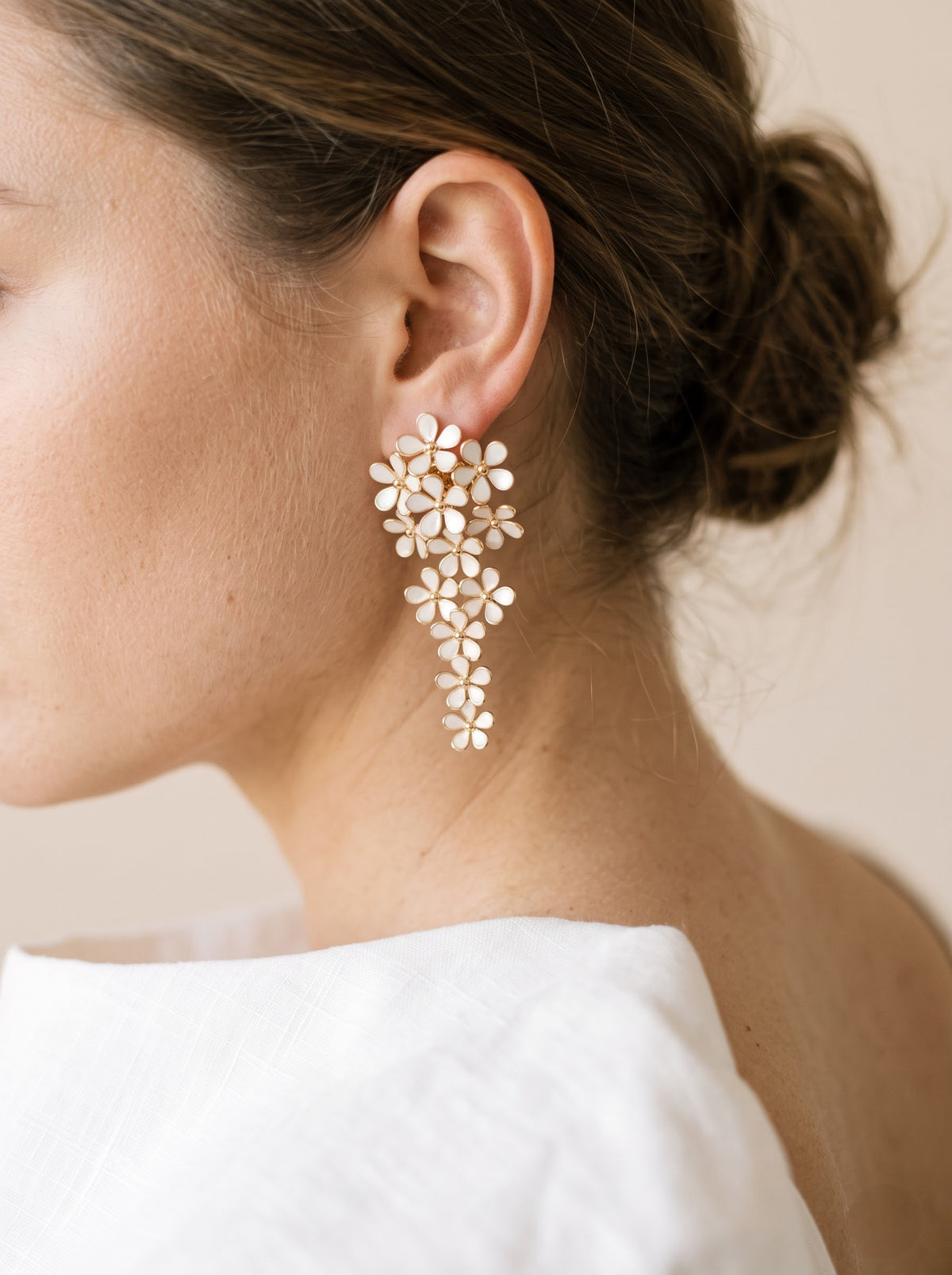 Side profile of a woman wearing a StoneCraft Jewellery white floral cascade earring with gold-plated outlines.