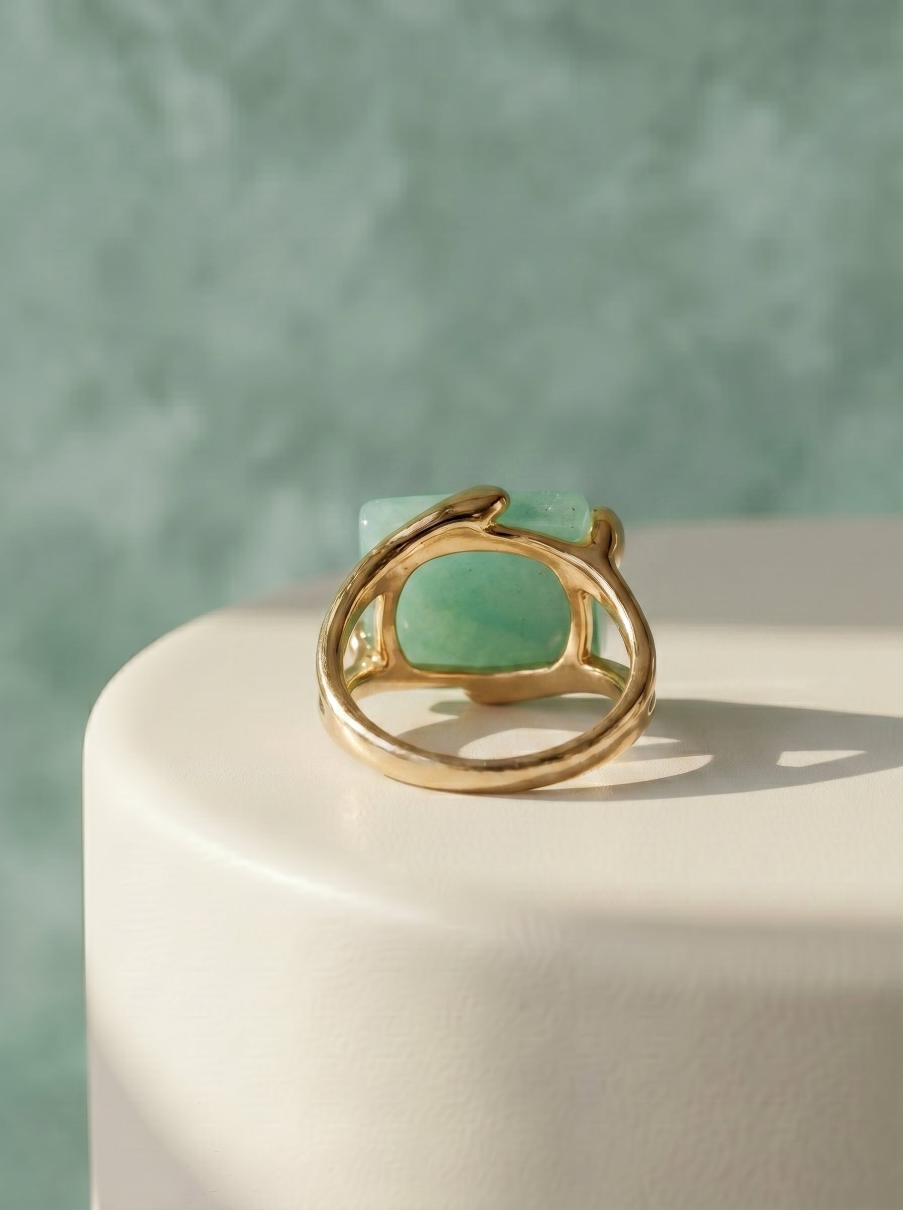 Natural green quartz rectangular statement ring on gold-plated band displayed on a white surface