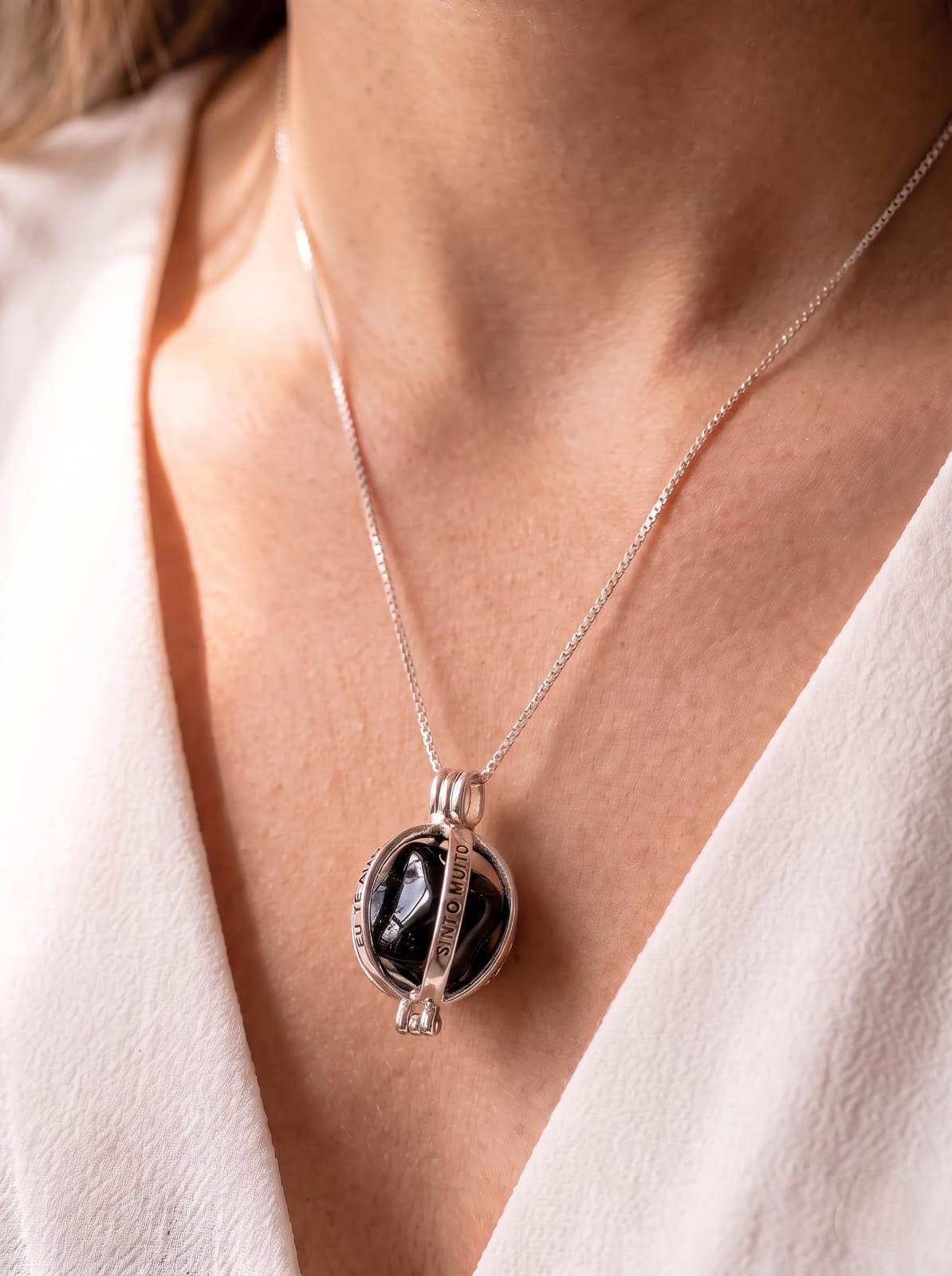 Woman wearing StoneCraft Jewellery Angel Caller Necklace Rhodium Plated with Black Agate close-up on décolletage with white wrap top