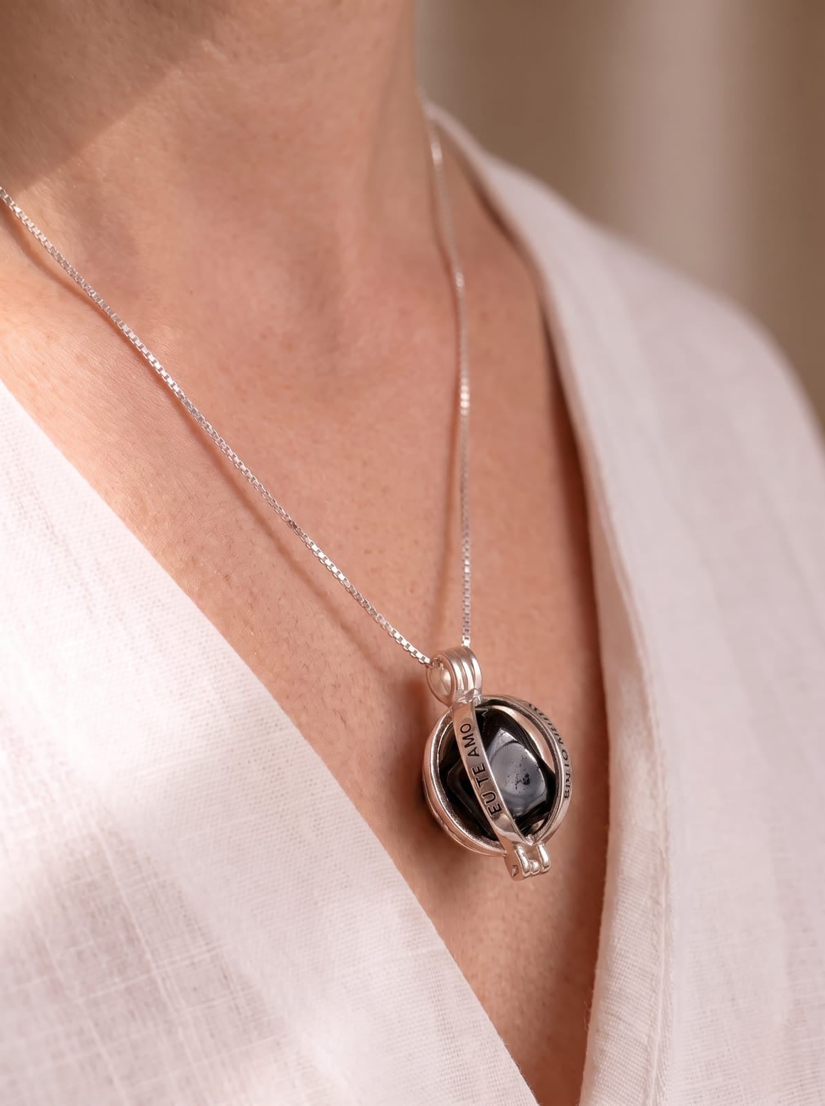 Woman wearing StoneCraft Jewellery Angel Caller Necklace Rhodium Plated with Black Agate full chest view on white linen top
