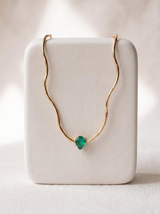 Gold-plated bamboo bar chain necklace with pear-cut green crystal solitaire displayed on a white jewellery stand