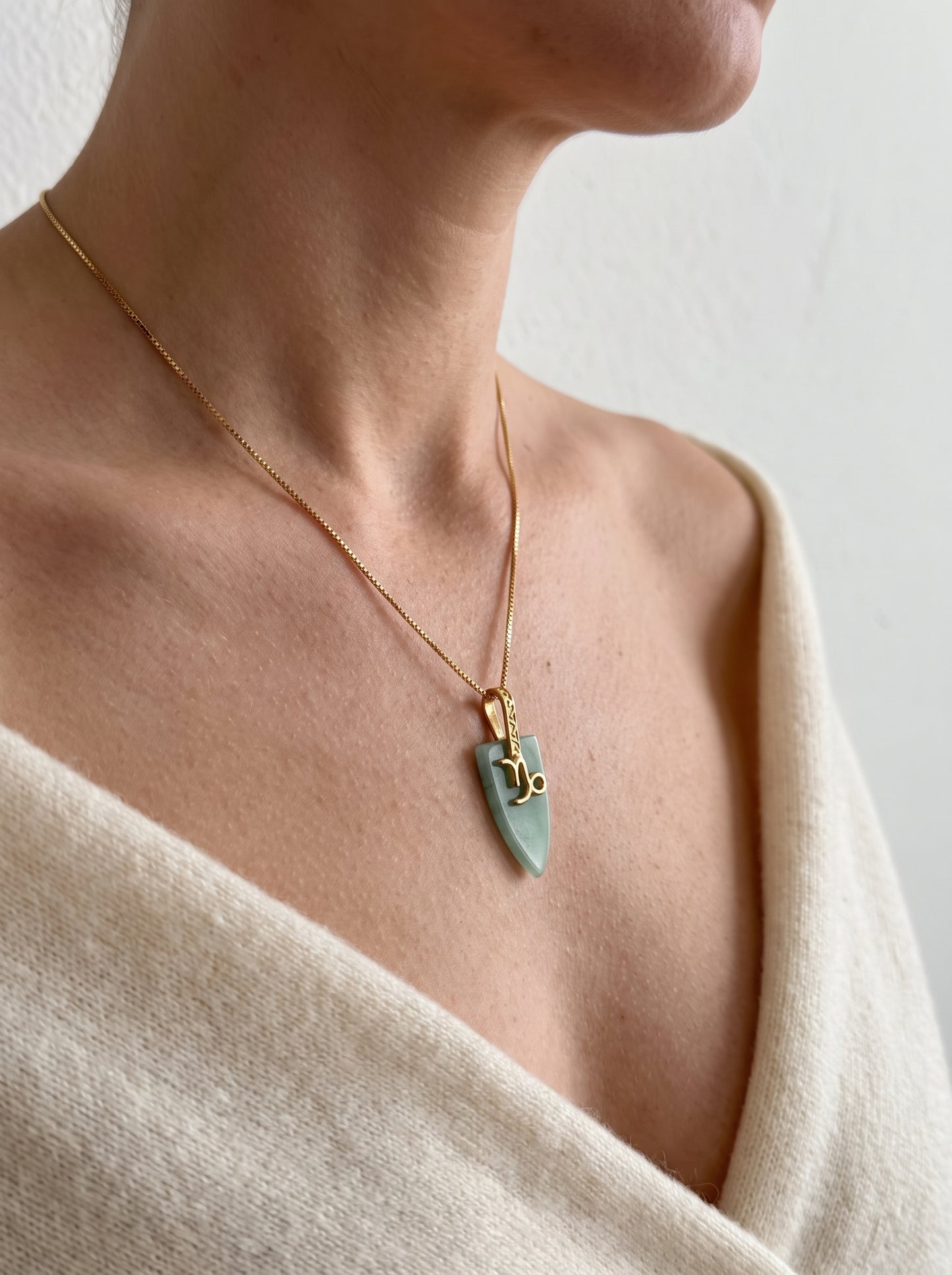 gold-plated Capricorn agate arrowhead pendant necklace worn by a woman in a cream wrap top