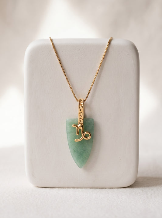 Gold-plated box chain necklace with green agate arrowhead pendant and Capricorn zodiac symbol displayed on a white jewellery stand