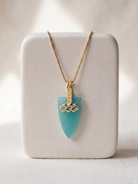 Gold-plated box chain necklace with aqua agate arrowhead pendant and Aquarius zodiac bail displayed on a white jewellery stand