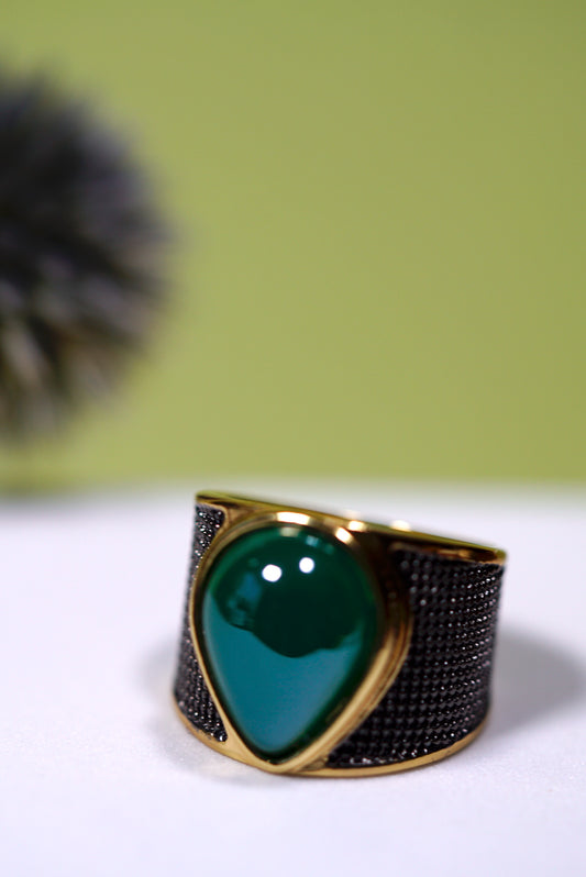 wide band Gold ring with a  pear shape green agate gemstone on a white surface with a green background