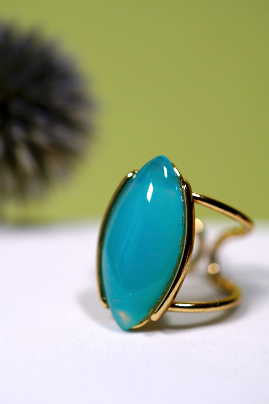 Marquise Teal  aqua agate ring with gold cuff band on a white surface with a green background