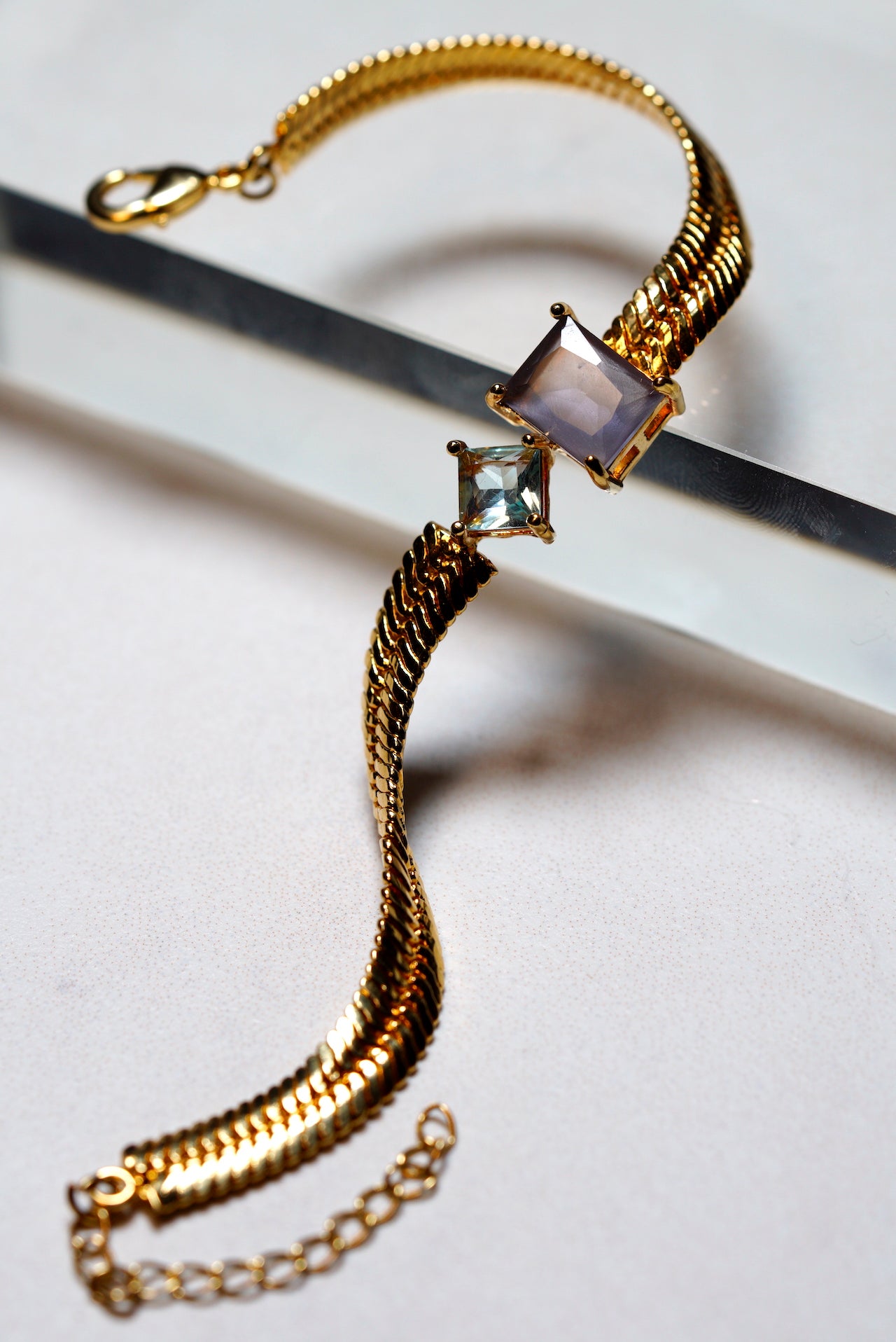 Snake Gold bracelet with square gemstones on a light background