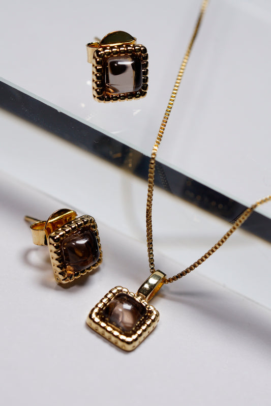 Gold jewellery set with smoky quartz square pendant and  stud earrings on a white background