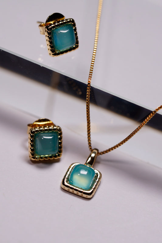 Jewellery set with gold chain, Aqua agate hammered square dainty pendant, and aqua agate hammered square stud earrings on a reflective surface.